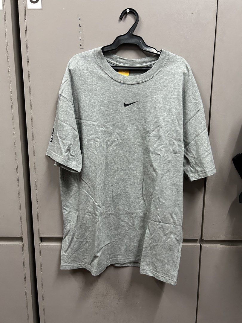 Nike NOCTA Grey T-shirt (Category: Tshirts & Polo Shirts ) located in Manila. Submitted by _sortezhitz (Listing ID 1423442178, Image 1). Description: - Grey Nike NOCTA T-shirt - Small Nike logo on the front - Large black NOCTA logo on the back - Short sleeves - Crew neck - Small logo on the left sleeve - Nike Store bought .