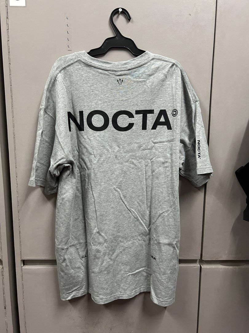 Nike NOCTA Grey T-shirt (Category: Tshirts & Polo Shirts ) located in Manila. Submitted by _sortezhitz (Listing ID 1423442178, Image 2). Description: - Grey Nike NOCTA T-shirt - Small Nike logo on the front - Large black NOCTA logo on the back - Short sleeves - Crew neck - Small logo on the left sleeve - Nike Store bought .