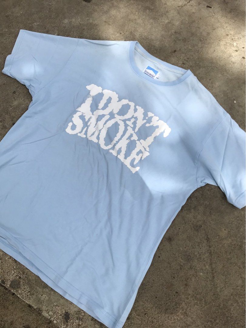 Blue "I Don't Smoke" Graphic Tee (Category: Tshirts & Polo Shirts ) located in Parang, Maguindanao. Submitted by jedthrift21 (Listing ID 1423629598, Image 1). Description: - Light blue t-shirt - Features a white graphic that says "I Don't Smoke" - Crew neck design - Short sleeves - Made of soft material - Brand tag visible.