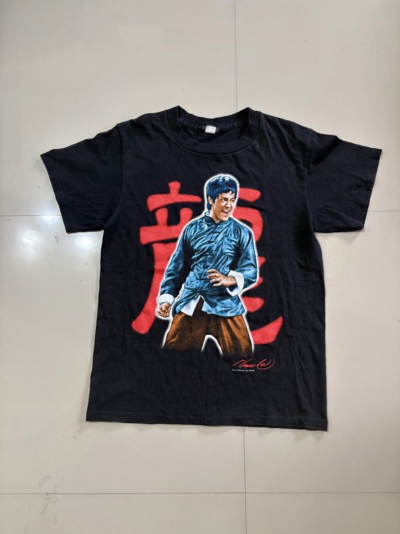 Bruce Lee Vintage T-Shirt (Category: Tshirts & Polo Shirts ) located in Lipa City. Submitted by thriftopia_sj (Listing ID 1423664999, Image 2). Description: - Vintage Bruce Lee t-shirt - Features a front graphic of Bruce Lee in a blue outfit with red Chinese characters - Back of shirt has the Bruce Lee logo in red - From the Bruce Lee Estate - Tag: Changes 20x28 Changes Tag.