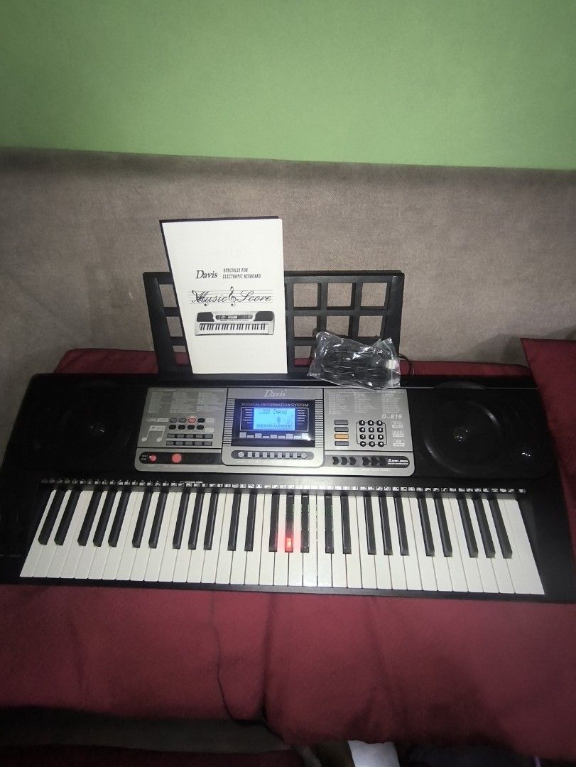 Davis D-816 Digital Keyboard (Category: Musical Instruments) located in Manila. Submitted by bonsai13 (Listing ID 1423694717, Image 1). Description: -Davis 816 Digital Keyboard -61 Touch Sensitive Keys -Light Up Keys -Built in teaching programs -Like new with Box -Bought Feb 20, 2026 -Still under warranty -Includes a music score, power adapter, and a music stand. -The keyboard has a black body with white and black keys..