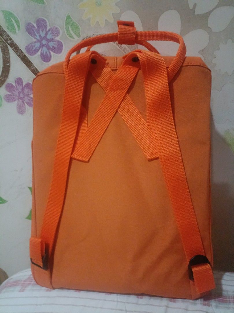 Fjallraven Kanken Classic Backpack - Orange (Category: Backpacks) located in Cebu City. Submitted by dediosmark83726 (Listing ID 1423703676, Image 2). Description: Fjallraven Kanken Classic backpack is in a vibrant orange color. It features the iconic Fjallraven logo on the front and has a classic square design. The backpack includes a front pocket, side pockets, and adjustable straps. The interior has a tag with the Fjallraven logo and informati