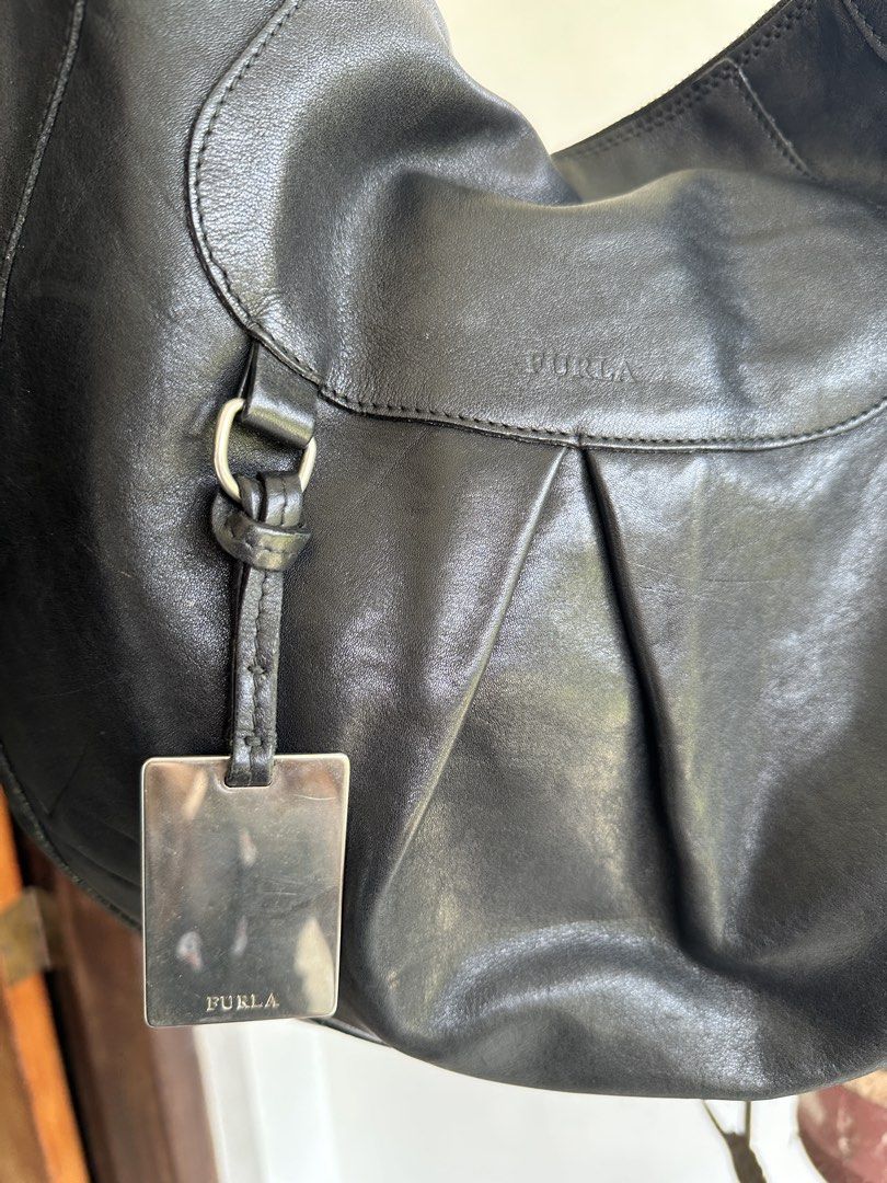 Furla Black Leather Hobo Bag (Category: Luxury Bags & Wallets) located in Bombon. Submitted by cookiespreloveed (Listing ID 1423751256, Image 2). Description: - Furla black leather hobo bag - Silver-tone metal tag and hardware - Secure zipper closure - Spacious interior with Furla logo lining - Comfortable shoulder strap - Durable YKK zipper.