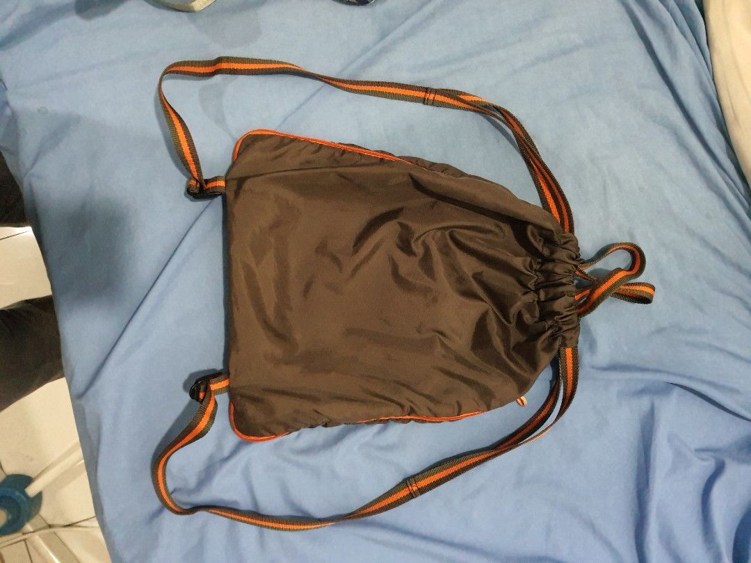 GAP Drawstring Backpack (Category: Backpacks) located in Kuala Lumpur. Submitted by imtheg (Listing ID 1423628183, Image 3). Description: - Good Condition - GAP drawstring backpack - Brown body with orange accents - Front zip pocket with GAP logo - Orange and brown striped straps - Made of nylon-like material - Simple and practical design.