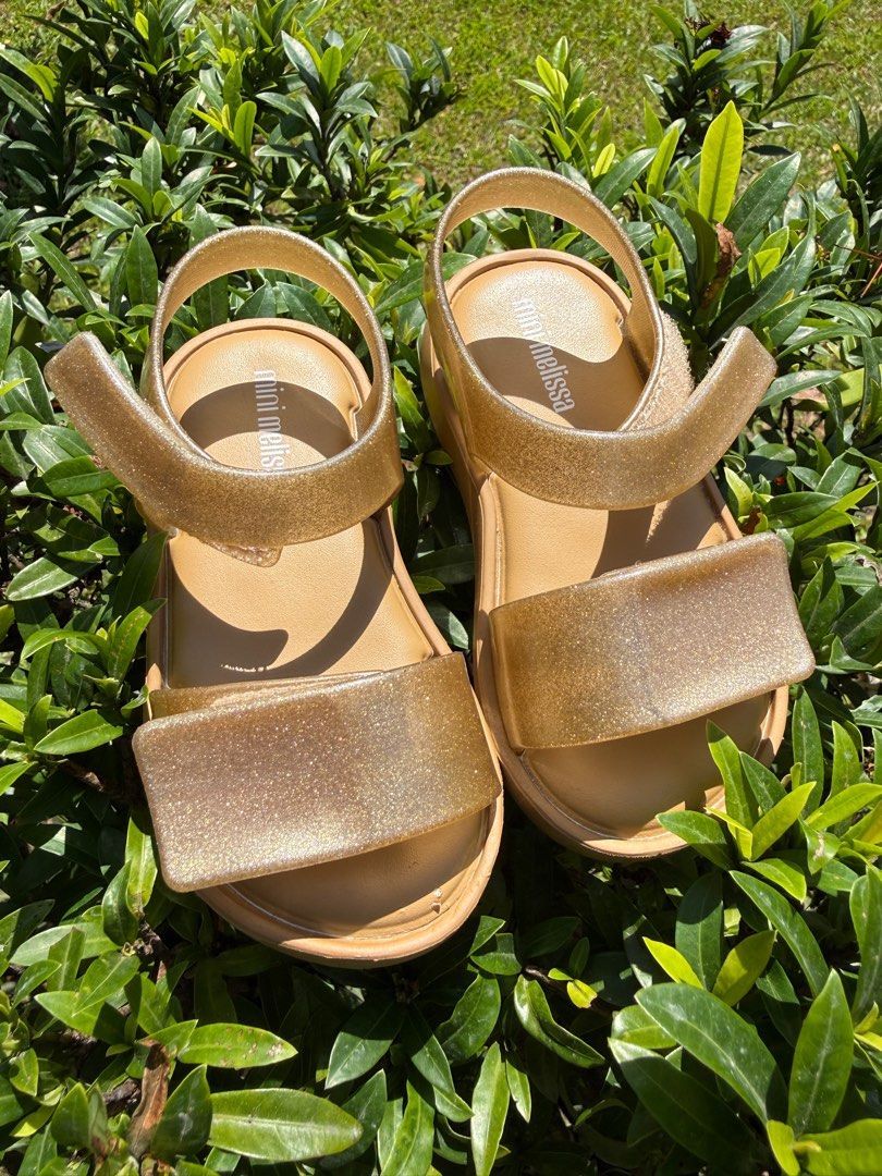 Mini Melissa Gold Sandals Size 8 (Category: Babies & Kids Fashion) located in Bacacay. Submitted by janinealvarado (Listing ID 1423686526, Image 1). Description: - Gold Mini Melissa sandals - Size: US 8 / EUR 22 / 14.5 CM - Platform sole - Glittery finish - Made in Brazil - Vegan Brandnew but with flaw (no box) ❌NO FREE SHIPPING❌.