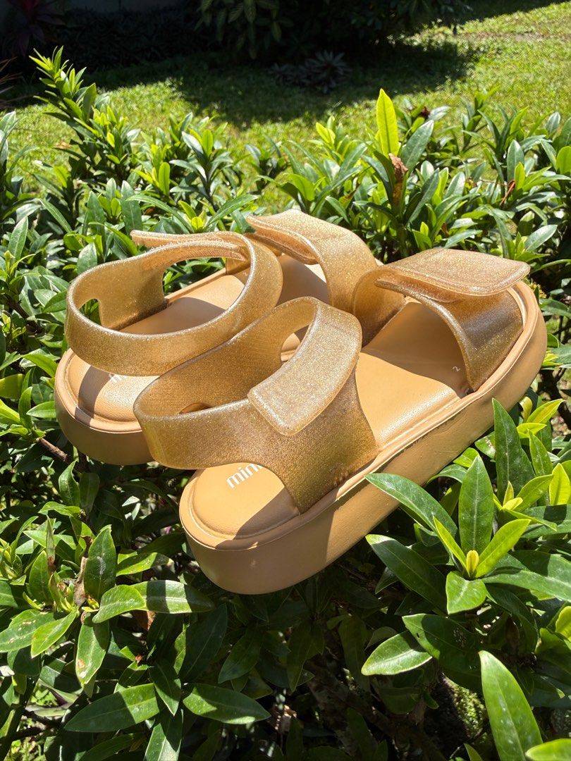 Mini Melissa Gold Sandals Size 8 (Category: Babies & Kids Fashion) located in Bacacay. Submitted by janinealvarado (Listing ID 1423686526, Image 2). Description: - Gold Mini Melissa sandals - Size: US 8 / EUR 22 / 14.5 CM - Platform sole - Glittery finish - Made in Brazil - Vegan Brandnew but with flaw (no box) ❌NO FREE SHIPPING❌.