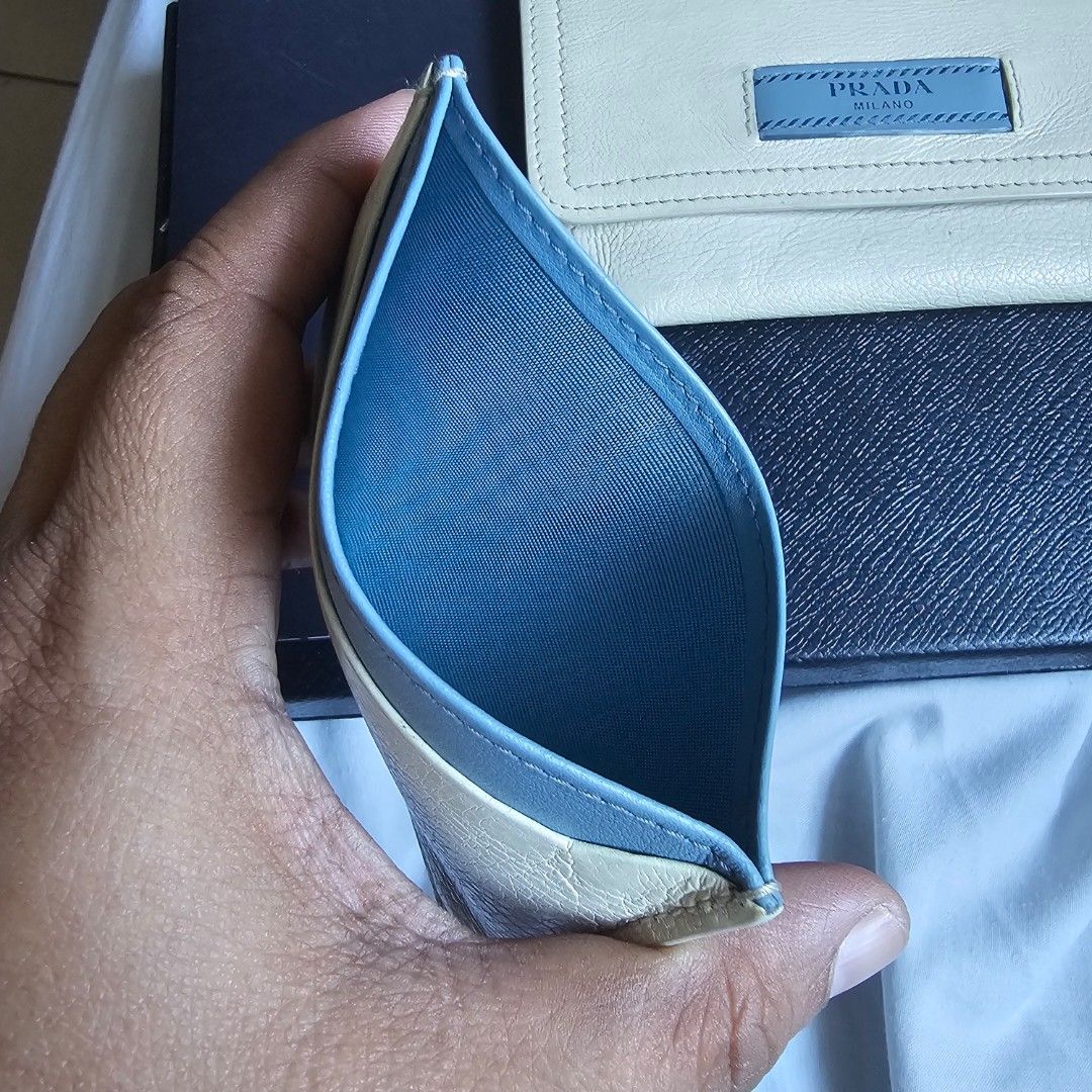 Prada Card Holder with Box (Category: Luxury Bags & Wallets) located in Batangas. Submitted by iammrs (Listing ID 1423655096, Image 3). Description: Prada card holder in cream and blue. Features a snap closure and multiple card slots. Includes the original box and receipt. The interior is cream-colored leather with the "Prada Made in Italy" stamp. The exterior has a blue Prada logo. The card holder has a slim profile..