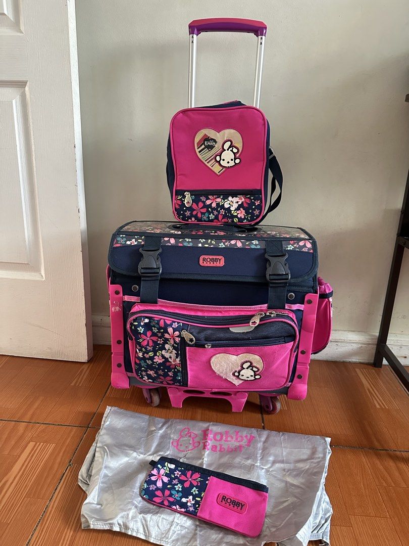 Robby Rabbit trolley school bag (Category: Babies & Kids Fashion) located in Cainta. Submitted by kath_pl (Listing ID 1423639381, Image 3). Description: Robby Rabbit rolling backpack set includes a rolling backpack, a detachable small bag, and a pencil case. The set features a pink and navy blue floral design with a cute bunny motif. The backpack has multiple compartments and a retractable handle..