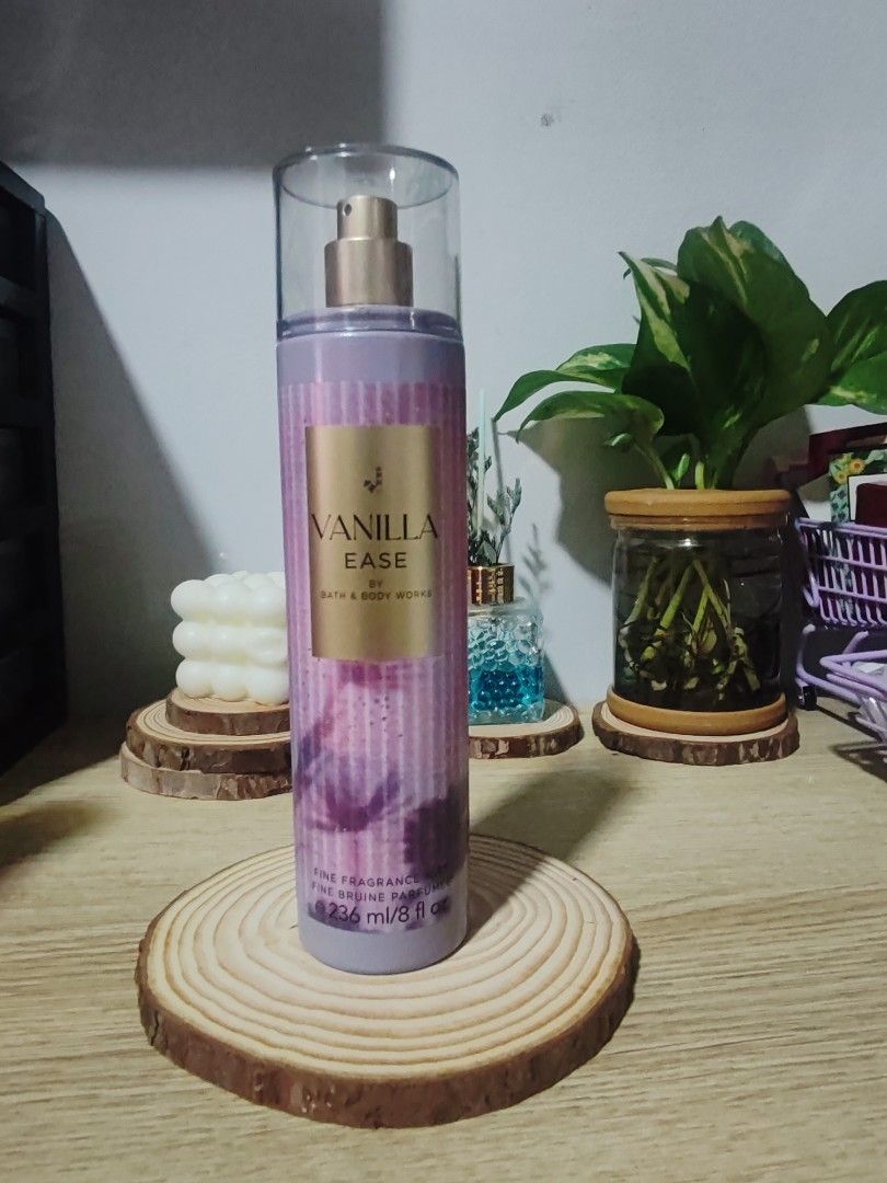 Bath & Body Works Vanilla Ease Fine Fragrance Mist (Category: Fragrance & Deodorants) located in San Fernando. Submitted by bcj.valuables (Listing ID 1423823021, Image 1). Description: - Bath & Body Works Vanilla Ease Fine Fragrance Mist - Size: 236 ml / 8 fl oz - Bottle Design: Purple and pink with a gold label - Features a clear bottle with a gold spray nozzle - Product is displayed on a wooden coaster.