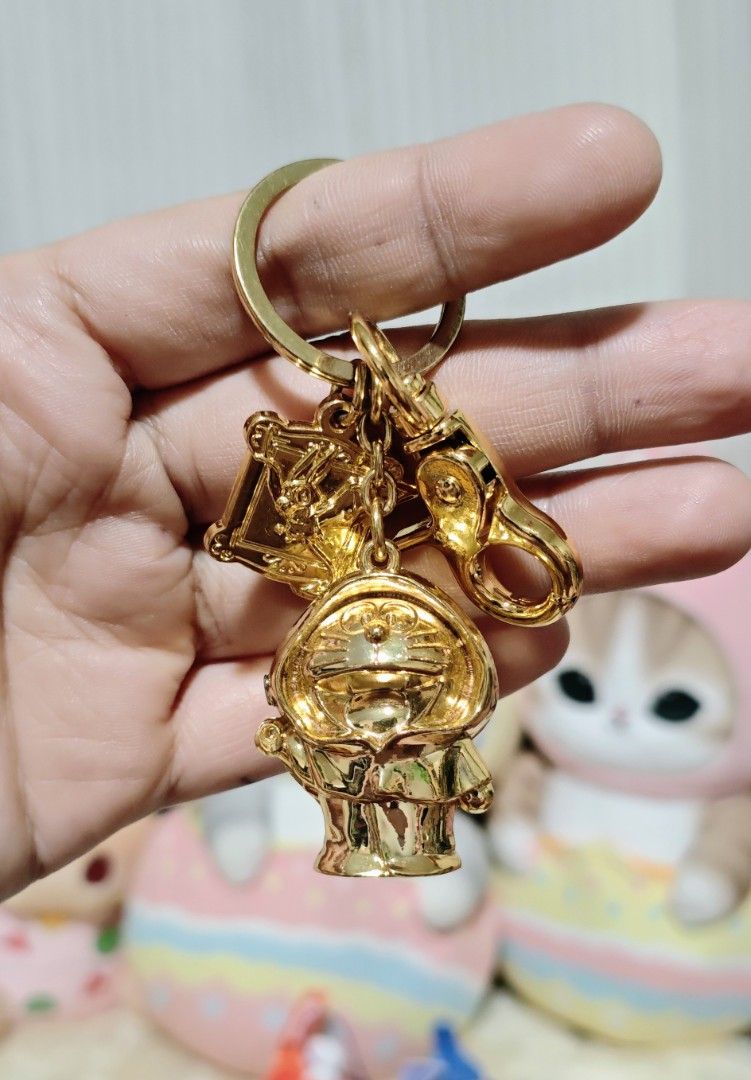 Doraemon Metal Keychain (Heavy) (Category: Character Goods) located in Manila. Submitted by yourfavoritethings7 (Listing ID 1423970301, Image 3). Description: - Gold-colored keychain - Features a Doraemon charm - Includes a small square charm with text on the back - Comes with a clasp for easy attachment - Ideal accessory for Doraemon enthusiasts.
