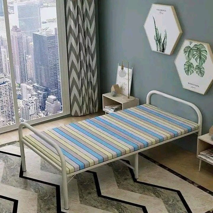 Foldable Single Bed (Category: Bed Frames & Mattresses) located in Makati City. Submitted by oideme (Listing ID 1423831717, Image 3). Description: Foldable single bed is perfect for small spaces. It features a striped mattress and a sturdy white metal frame. The bed is easy to set up and fold away for storage. It requires no installation and is portable. Dimensions are approximately 180cm long, 75cm wide, and 40cm high..
