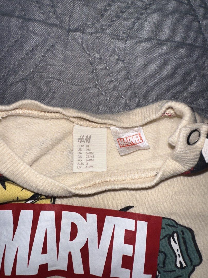 H&M Marvel Sweatshirt (Category: Babies & Kids Fashion) located in Bulacan. Submitted by dyna01 (Listing ID 1423846838, Image 2). Description: - H&M Marvel Sweatshirt - Size: 6-9 Months - Design: Marvel superhero faces - Color: Cream - Features: Long sleeves, round neckline, shoulder button closure - Details: Marvel logo on the front.