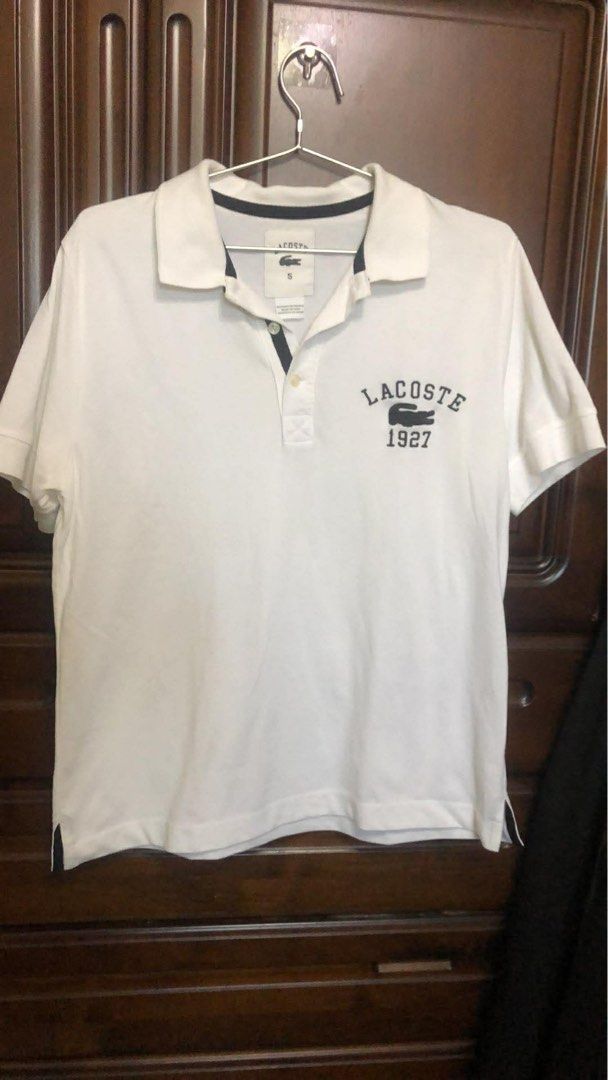 Lacoste 1927 White Polo Shirt (Category: Tshirts & Polo Shirts ) located in Batac City. Submitted by paudeclutterz (Listing ID 1423842381, Image 1). Description: - Lacoste polo shirt - Features the 1927 logo - Size 5 - Classic polo collar and short sleeves - Navy blue trim on collar and sleeves - Made of 100% cotton - Made in Peru - Designed in France.