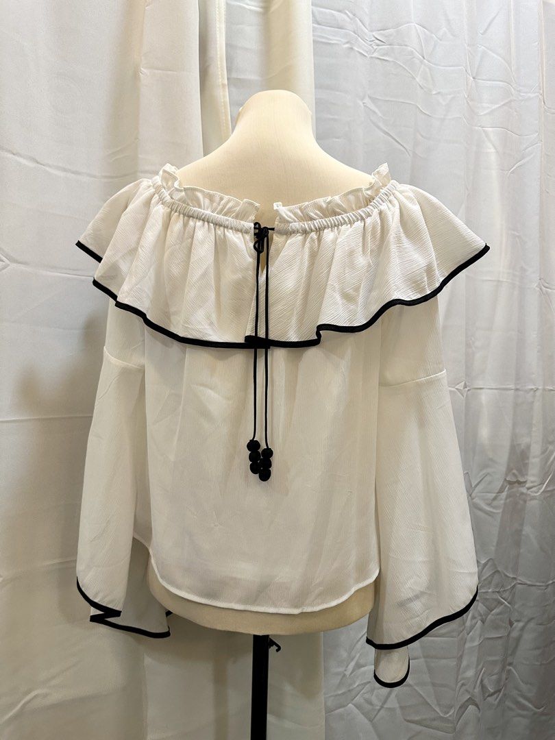 LEDIN Kiss Off-Shoulder Blouse (Category: Blouses) located in Manila. Submitted by randomdeclutter (Listing ID 1423957850, Image 2). Description: - White off-shoulder blouse - Black trim - Ruffled neckline - Bell sleeves - Tie-back detail with black beads - Size 38 (160/84A).