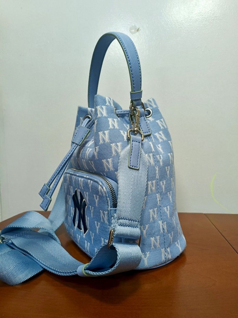 MLB New York Yankees Bucket Bag (Category: Cross-body Bags) located in Rizal. Submitted by amethyst_21794 (Listing ID 1423954187, Image 2). Description: - Light blue MLB bucket bag - All-over NY logo print - Drawstring closure - Top handle - Detachable shoulder strap - Front zipper pocket - Interior pocket - MLB logo detail.