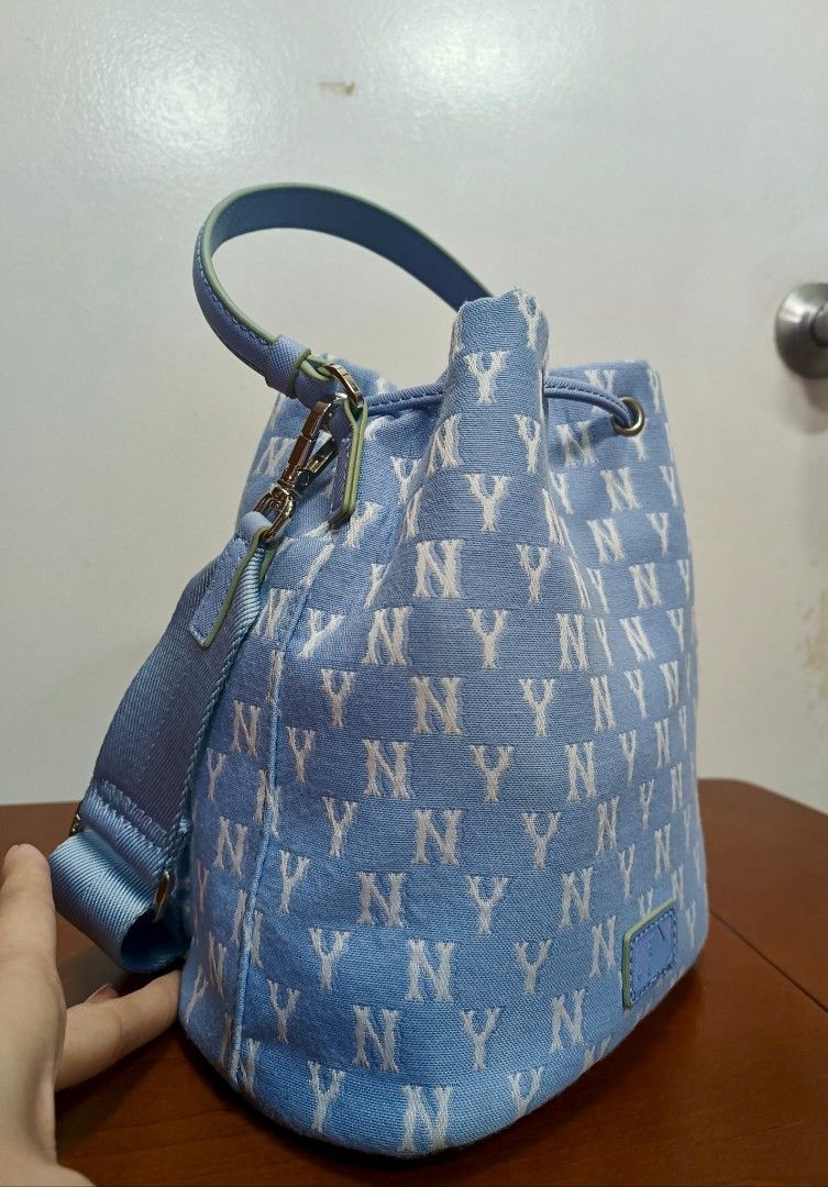 MLB New York Yankees Bucket Bag (Category: Cross-body Bags) located in Rizal. Submitted by amethyst_21794 (Listing ID 1423954187, Image 3). Description: - Light blue MLB bucket bag - All-over NY logo print - Drawstring closure - Top handle - Detachable shoulder strap - Front zipper pocket - Interior pocket - MLB logo detail.