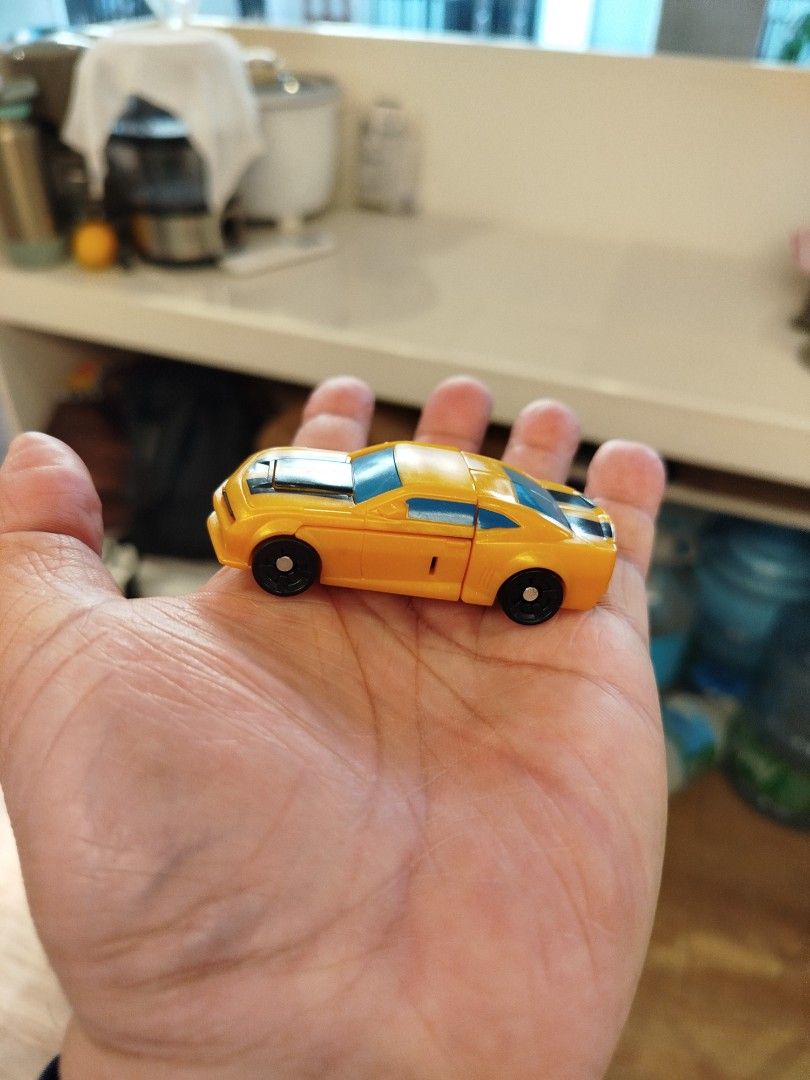 Transformers Bumblebee Toy Car (Category: Vehicle & Diecast Models) located in Caloocan City. Submitted by toys_r_here (Listing ID 1423873887, Image 1). Description: - Bumblebee toy car from Transformers. - Transforms into a robot. - Features: Yellow body, black stripes, and blue accents. - Black wheels. - Compact size: Fits in your hand..