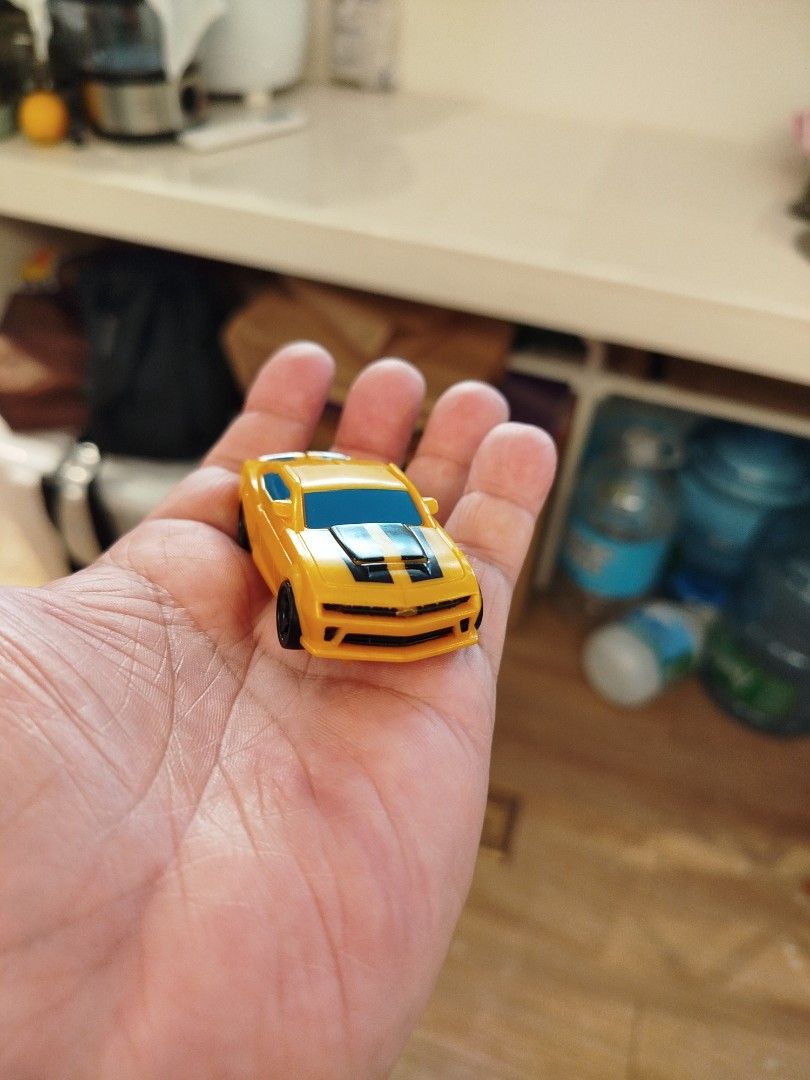 Transformers Bumblebee Toy Car (Category: Vehicle & Diecast Models) located in Caloocan City. Submitted by toys_r_here (Listing ID 1423873887, Image 2). Description: - Bumblebee toy car from Transformers. - Transforms into a robot. - Features: Yellow body, black stripes, and blue accents. - Black wheels. - Compact size: Fits in your hand..