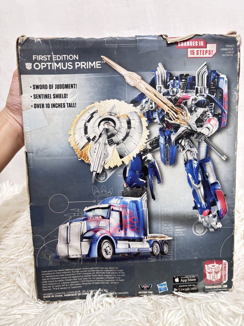Transformers First Edition Optimus Prime (Category: Action & Battle Toys) located in San Fernando. Submitted by ladychinita07 (Listing ID 1423860192, Image 3). Description: - First Edition Optimus Prime action figure - Includes sword of judgment and sentinel shield - Transforms in 15 steps - Over 10 inches tall - Box features robot and truck modes - Recommended for ages 8+ brand new but the box already has a dents.
