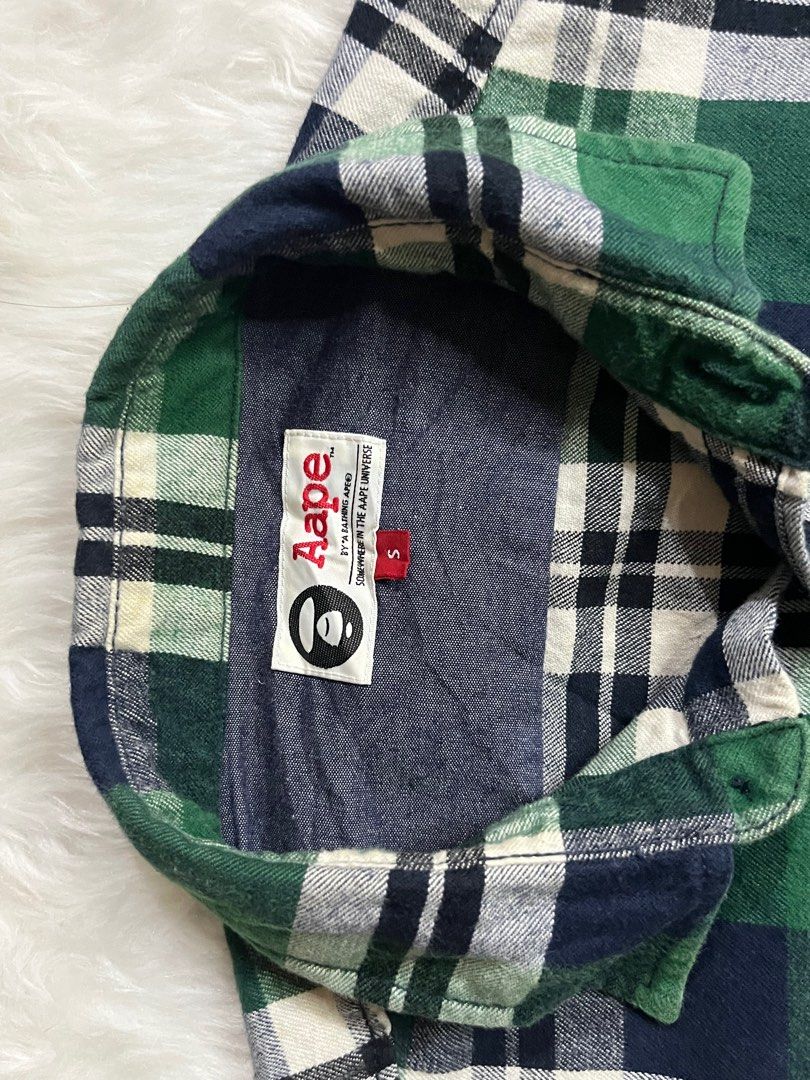 Aape by A Bathing Ape Plaid Shirt (Category: Tshirts & Polo Shirts ) located in Iloilo. Submitted by cloud.thrifts (Listing ID 1419541633, Image 3). Description: - Authentic Aape by A Bathing Ape shirt - Classic green, white, and navy blue plaid pattern - Features the Aape logo on the chest - Long sleeves with button-down closure - Includes a small logo tag - Made in China.