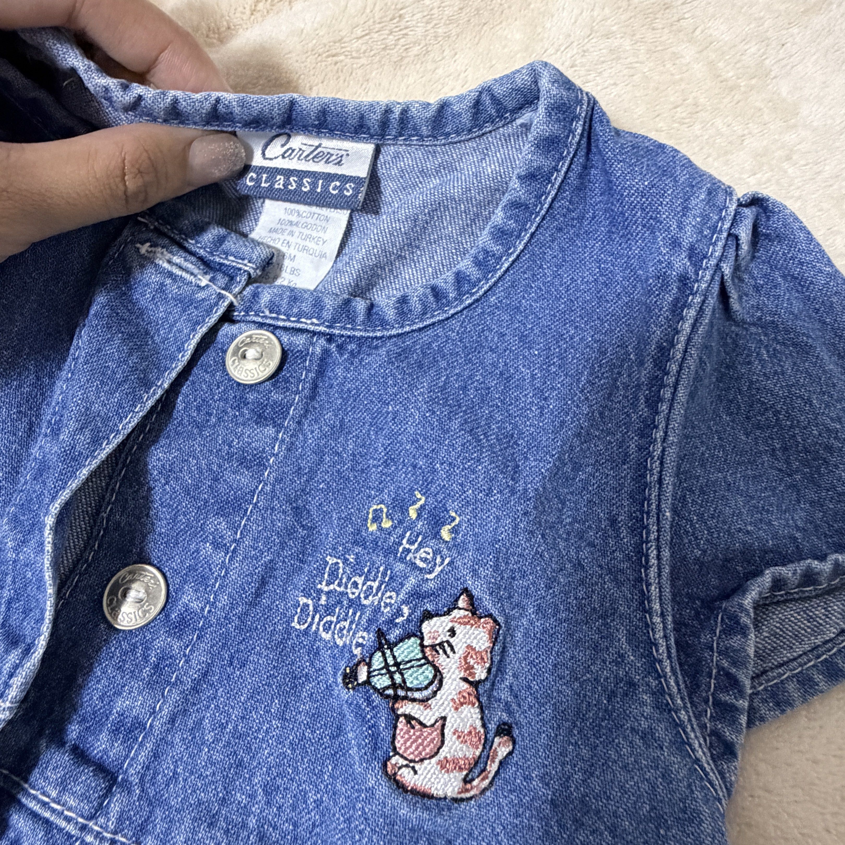 Carter's Classic Denim Dress (Category: Babies & Kids Fashion) located in Batangas. Submitted by chloclo.declutter (Listing ID 1419530079, Image 2). Description: 12-18 months - Carter's denim dress - Button-down front - Short sleeves - Embroidered cat playing violin - Gathered waist - Classic denim wash - Made in Turkey - Perfect for your little girl! Loc: Batangas Shipping via J&T.