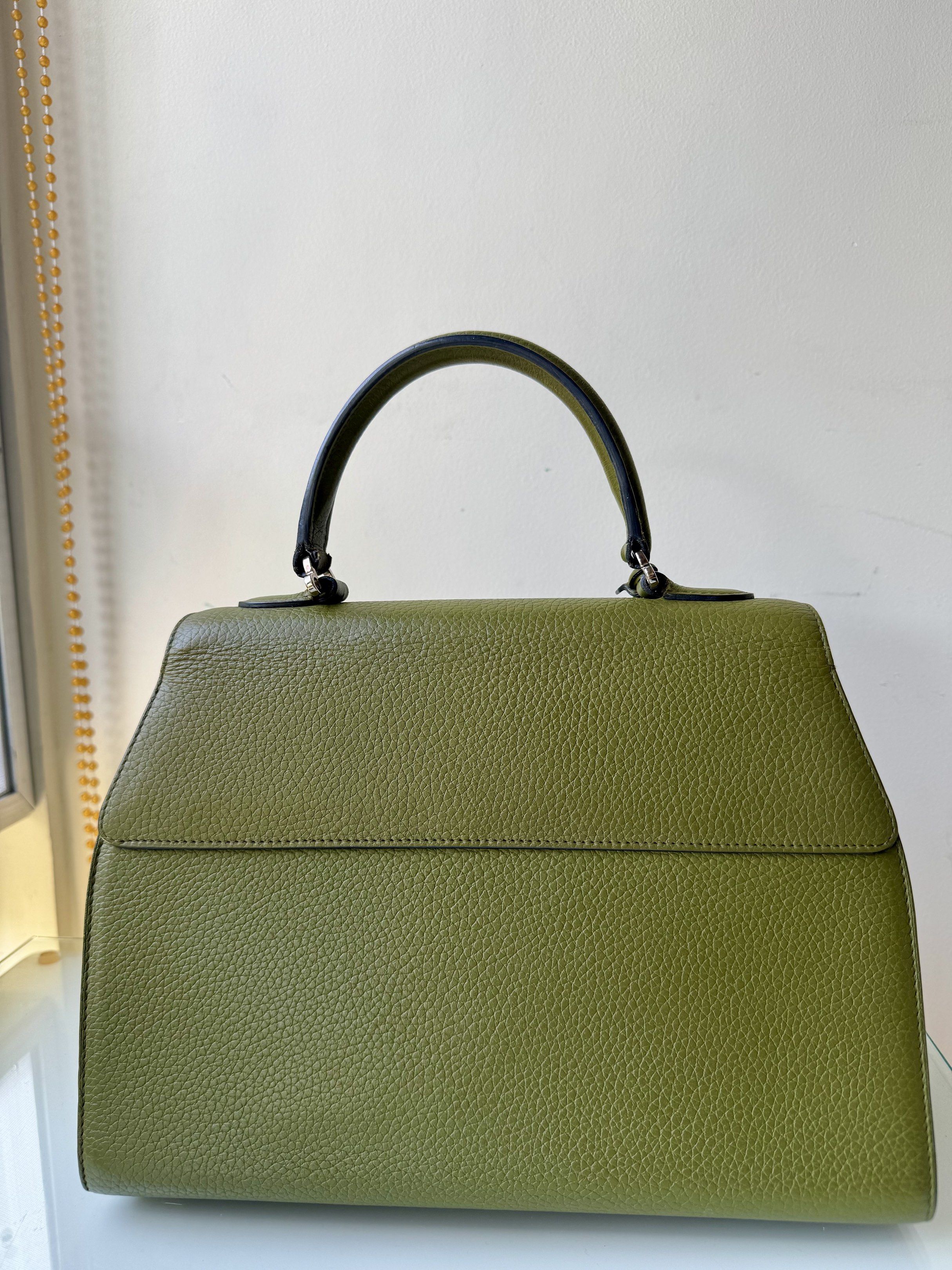 Green Leather Top Handle Bag (Category: Luxury Bags & Wallets) located in Muntinlupa City. Submitted by chelseanne_1 (Listing ID 1419407098, Image 2). Description: - Stylish green leather handbag - Top handle and detachable shoulder strap - Unique lock closure - Small leather tag - Textured leather - Structured shape - Black handle - Silver-toned hardware - Versatile accessory.