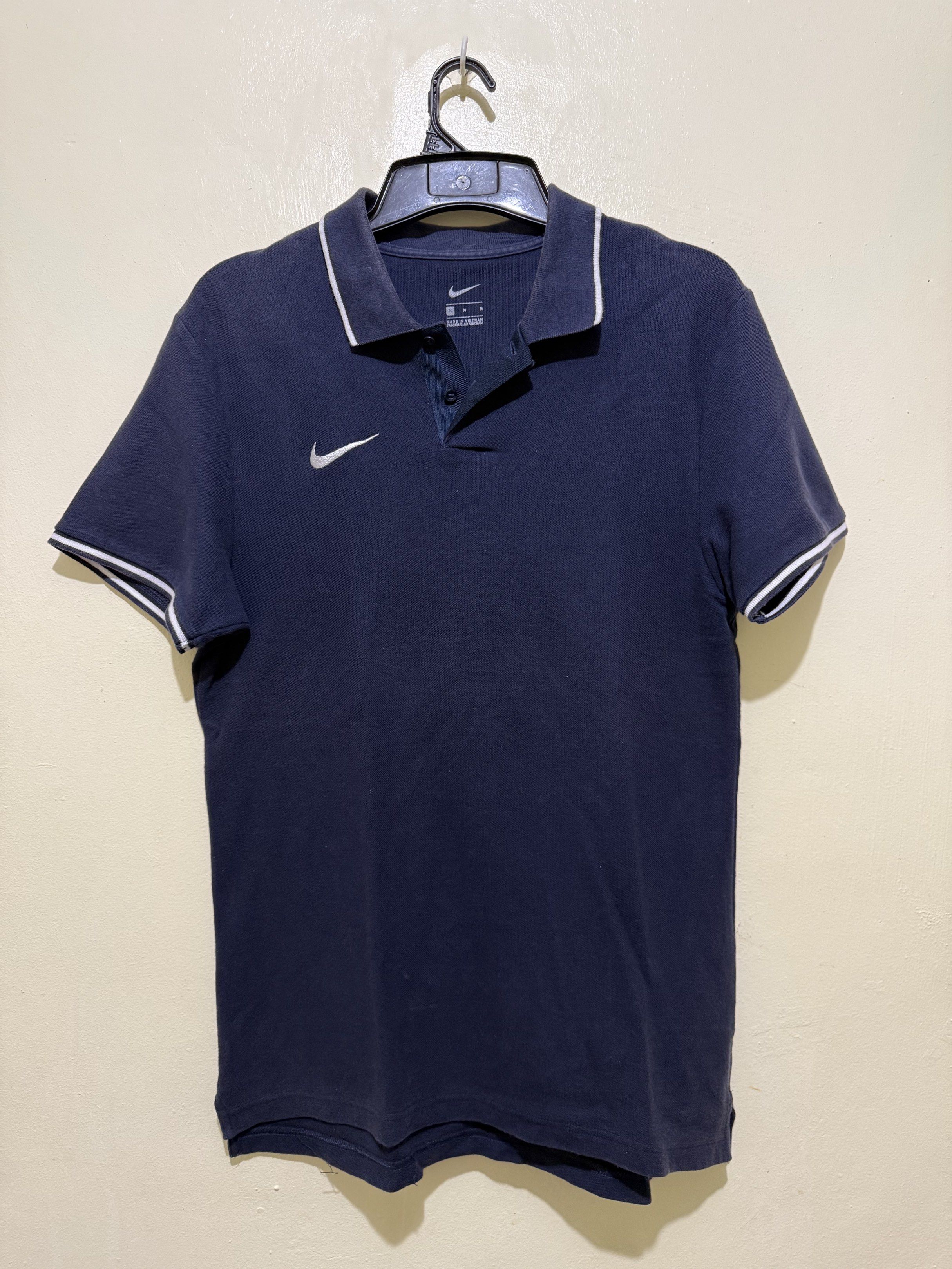 Nike Polo Shirt Navy Blue (Category: Tshirts & Polo Shirts ) located in Los Banos. Submitted by elbideclutter (Listing ID 1419500096, Image 1). Description: Navy blue Nike polo shirt with white trim on the collar and sleeves. Features the Nike logo on the left chest. It has a three-button placket and short sleeves. Relax Fit M See sample fit above.