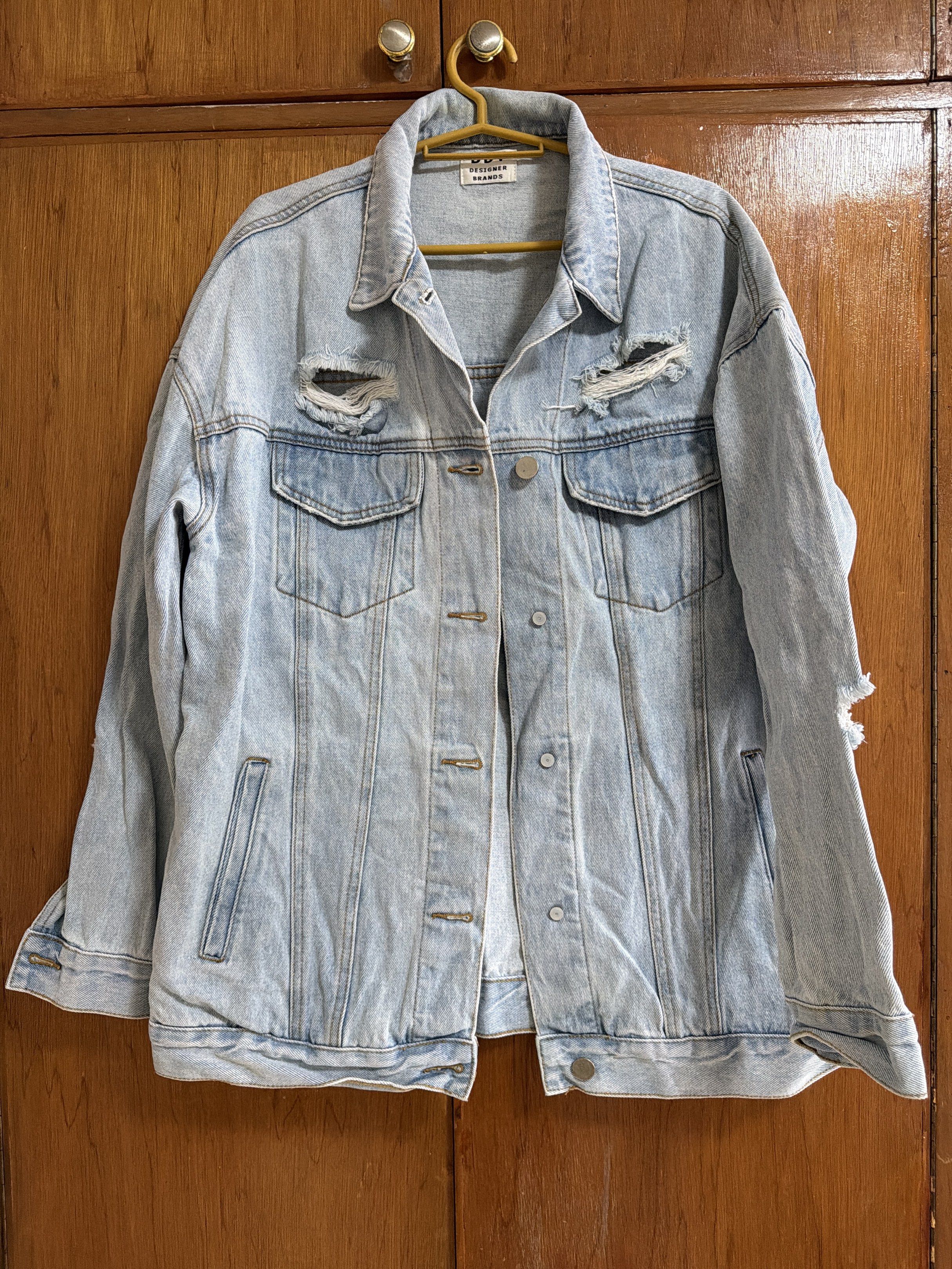 Oversized Denim Jacket (Category: Coats, Jackets and Outerwear) located in Manila. Submitted by dmdnice (Listing ID 1419440340, Image 1). Description: - DDY Designer Brands denim jacket - Light blue color - Distressed design with ripped details - Two chest pockets - Button closures - Classic collar - Relaxed fit - Perfect for layering.