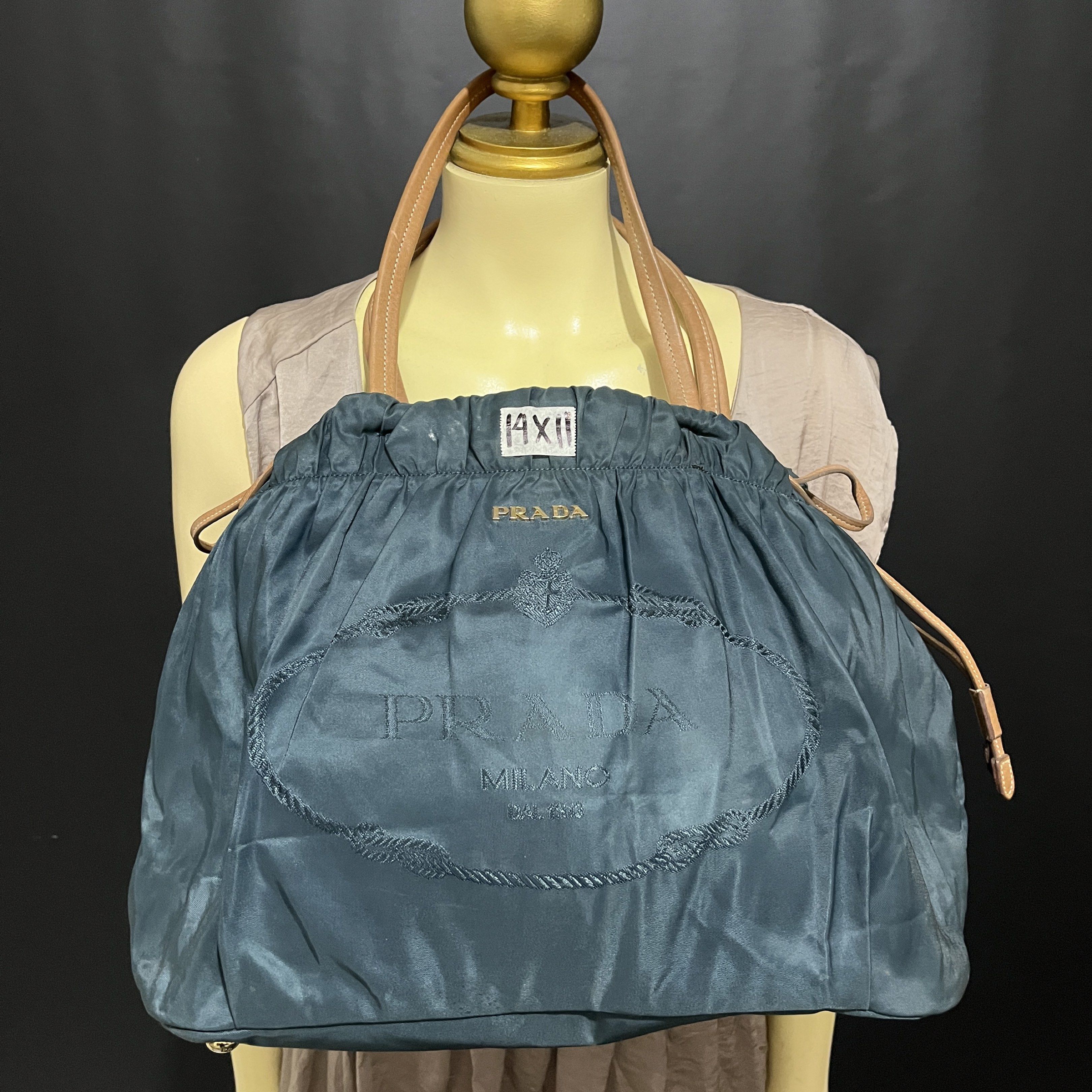 Prada Drawstring Tote Bag (Category: Luxury Bags & Wallets) located in Butuan. Submitted by dfgthriftology2.0 (Listing ID 1419544662, Image 1). Description: - Teal nylon exterior - Leather handles - Drawstring closure - Prada logo embroidery - Interior zipper pocket - Leather tag with Prada logo - Gold-tone hardware.