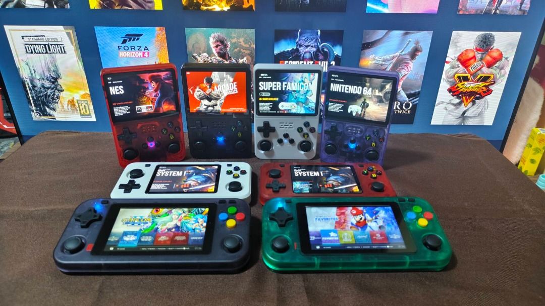 Retro Handheld Game Console (Category: Others) located in Davao. Submitted by leovanniem23152 (Listing ID 1419398131, Image 1). Description: Collection of retro handheld game consoles in various colors. Each console features a screen displaying different game interfaces. The consoles have a D-pad, buttons, and analog sticks. Some consoles show NES, Super Famicom, and Nintendo 64 game interfaces. The consoles come in red, black, white, gray, and g