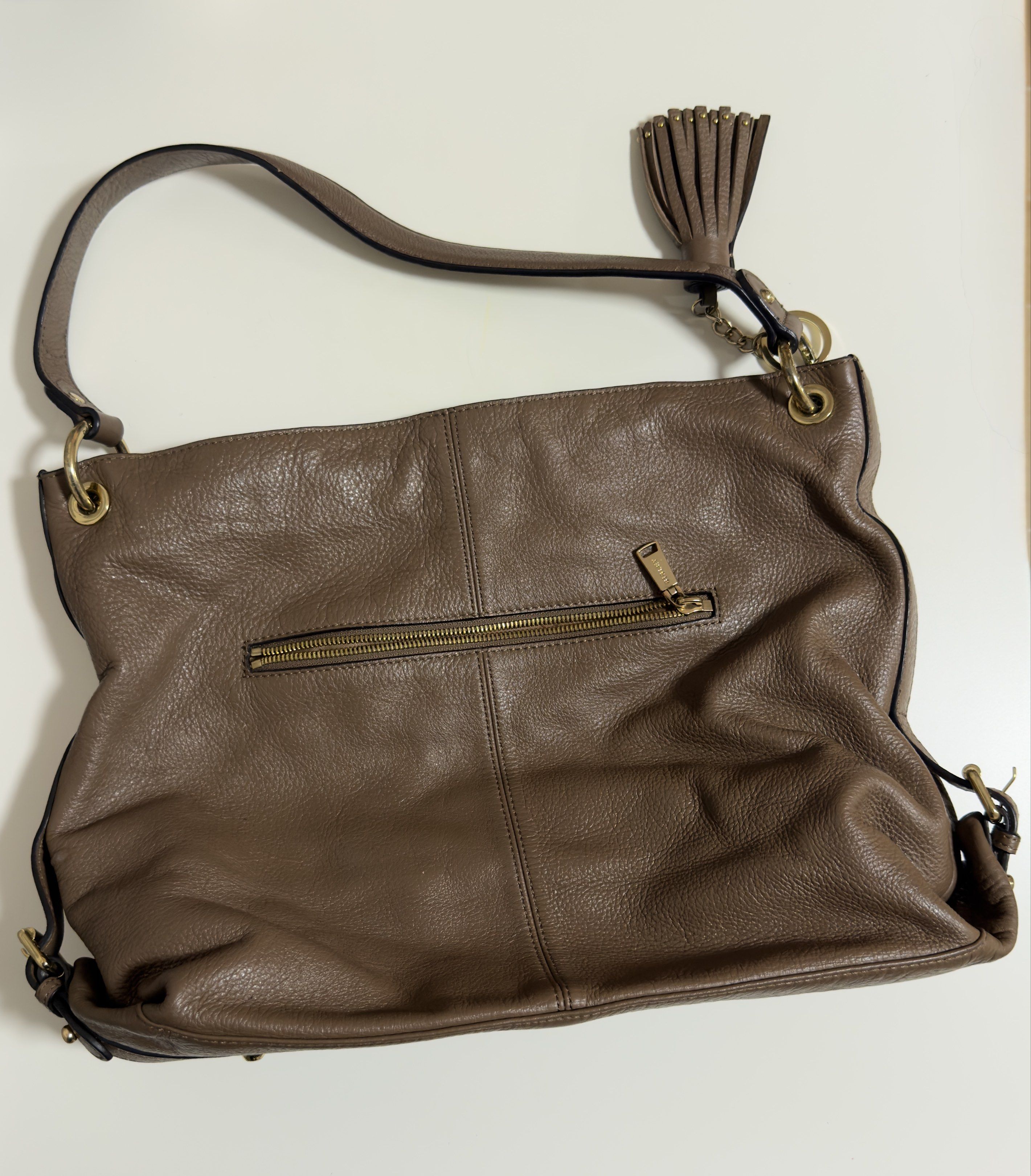 Sisley Shoulder Bag (Category: Shoulder Bags) located in Mandaluyong City. Submitted by gee028 (Listing ID 1419486807, Image 2). Description: - Sisley shoulder bag - Neutral brown color - Spacious interior with branded lining - Multiple pockets - Top handle - Decorative tassel - Gold-tone hardware - Zipper closure - Sisley logo on exterior.