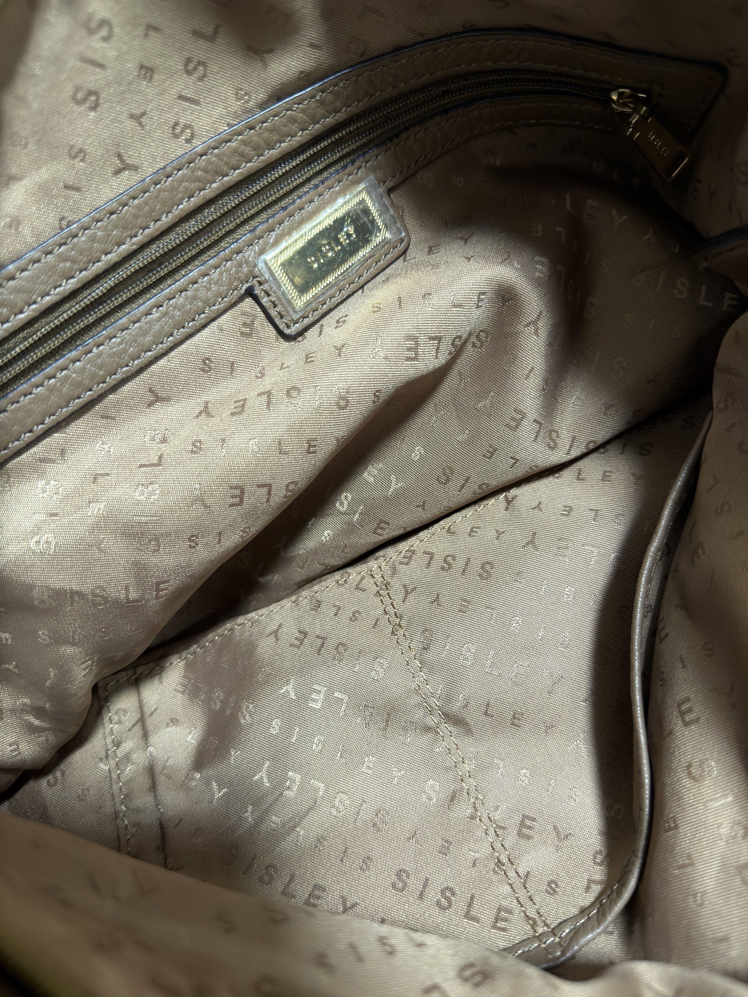 Sisley Shoulder Bag (Category: Shoulder Bags) located in Mandaluyong City. Submitted by gee028 (Listing ID 1419486807, Image 3). Description: - Sisley shoulder bag - Neutral brown color - Spacious interior with branded lining - Multiple pockets - Top handle - Decorative tassel - Gold-tone hardware - Zipper closure - Sisley logo on exterior.