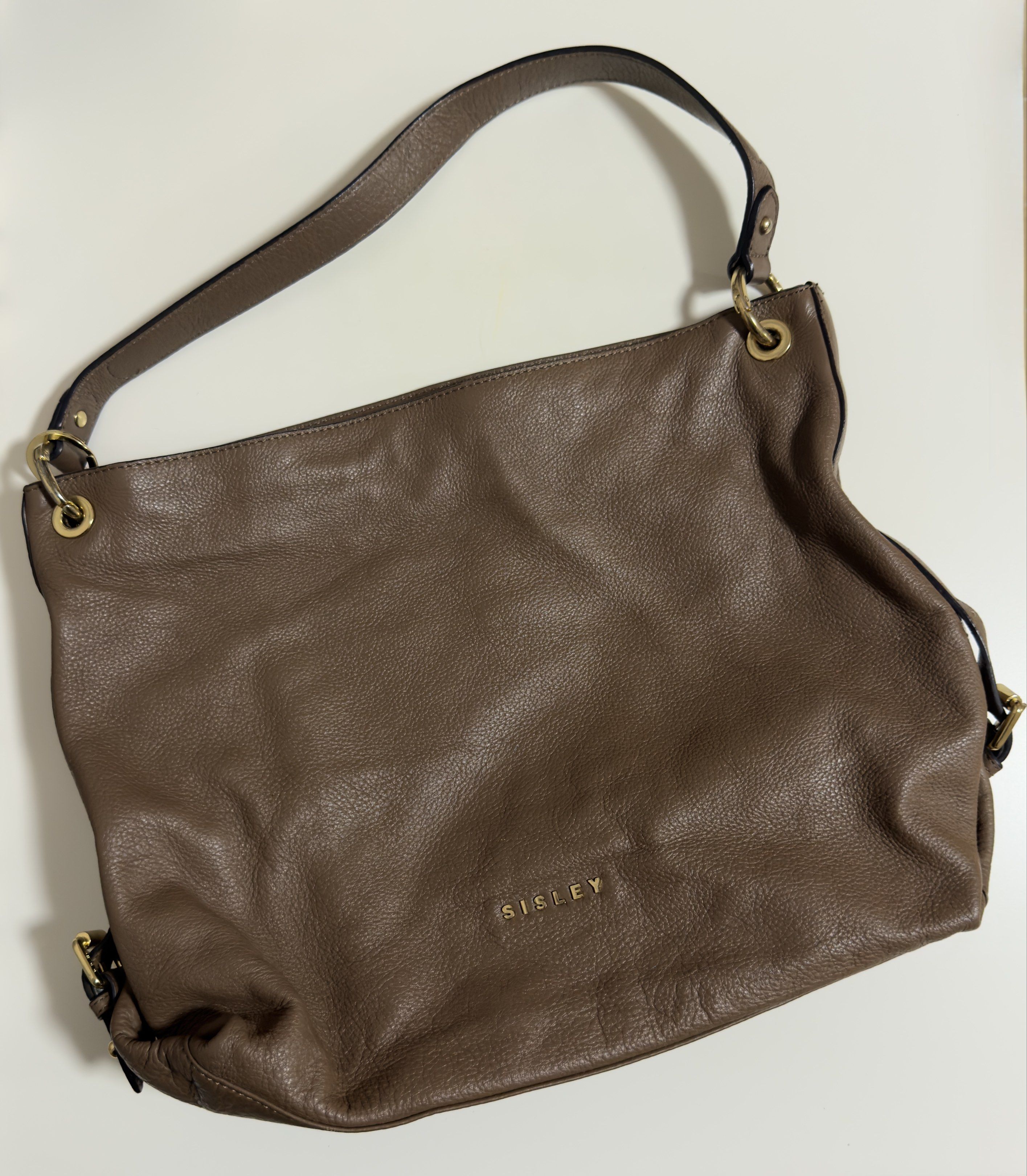 Sisley Shoulder Bag (Category: Shoulder Bags) located in Mandaluyong City. Submitted by gee028 (Listing ID 1419486807, Image 1). Description: - Sisley shoulder bag - Neutral brown color - Spacious interior with branded lining - Multiple pockets - Top handle - Decorative tassel - Gold-tone hardware - Zipper closure - Sisley logo on exterior.