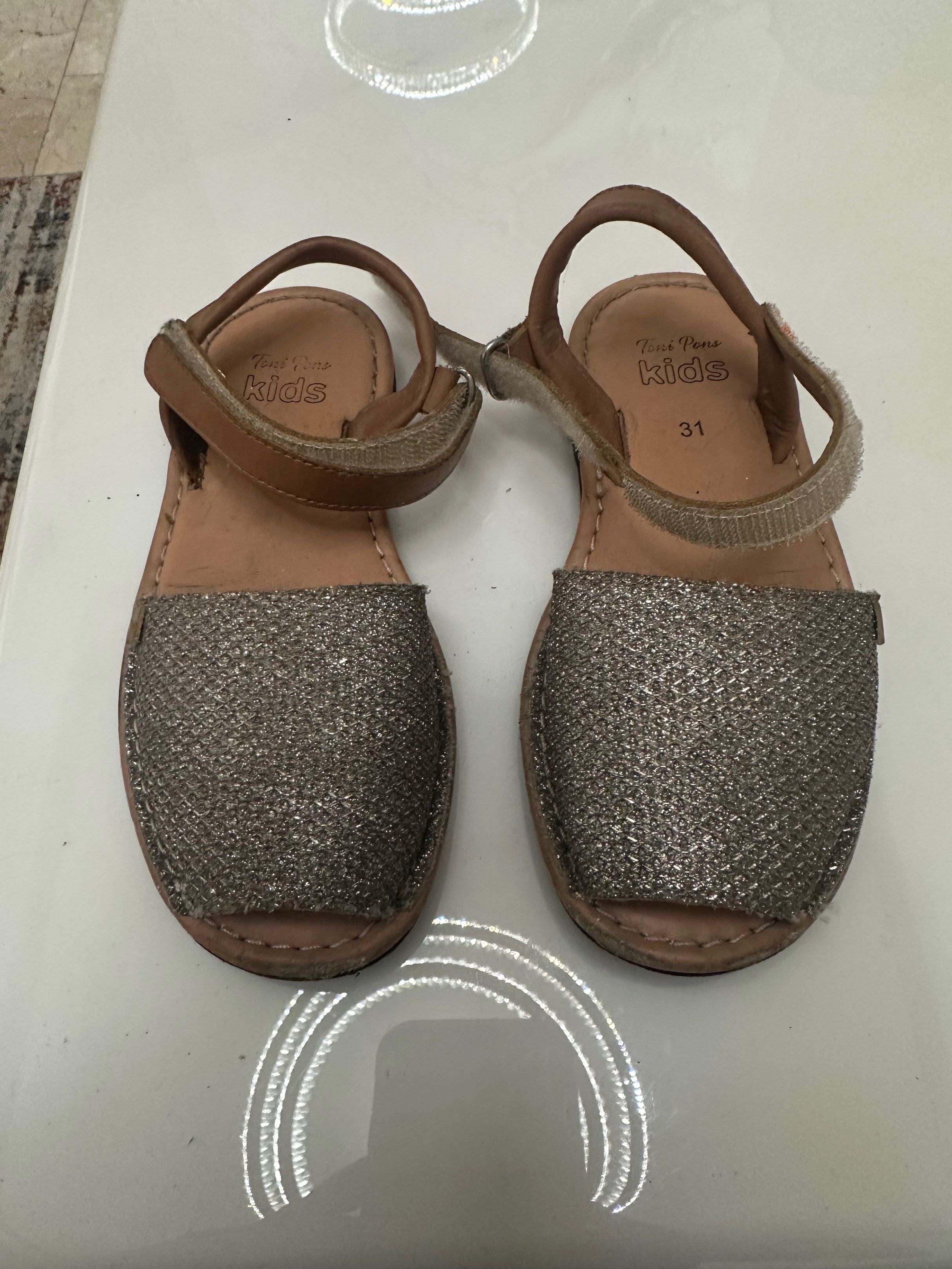 Toni Pons kids shoes (Category: Babies & Kids Fashion) located in Antipolo. Submitted by capizexport (Listing ID 1419523745, Image 2). Description: - Toni Pons - Size 31 - Silver glitter upper - Brown leather strap - Black soles with textured pattern - Hook-and-loop closure - Well-maintained condition Price 500 pesos .