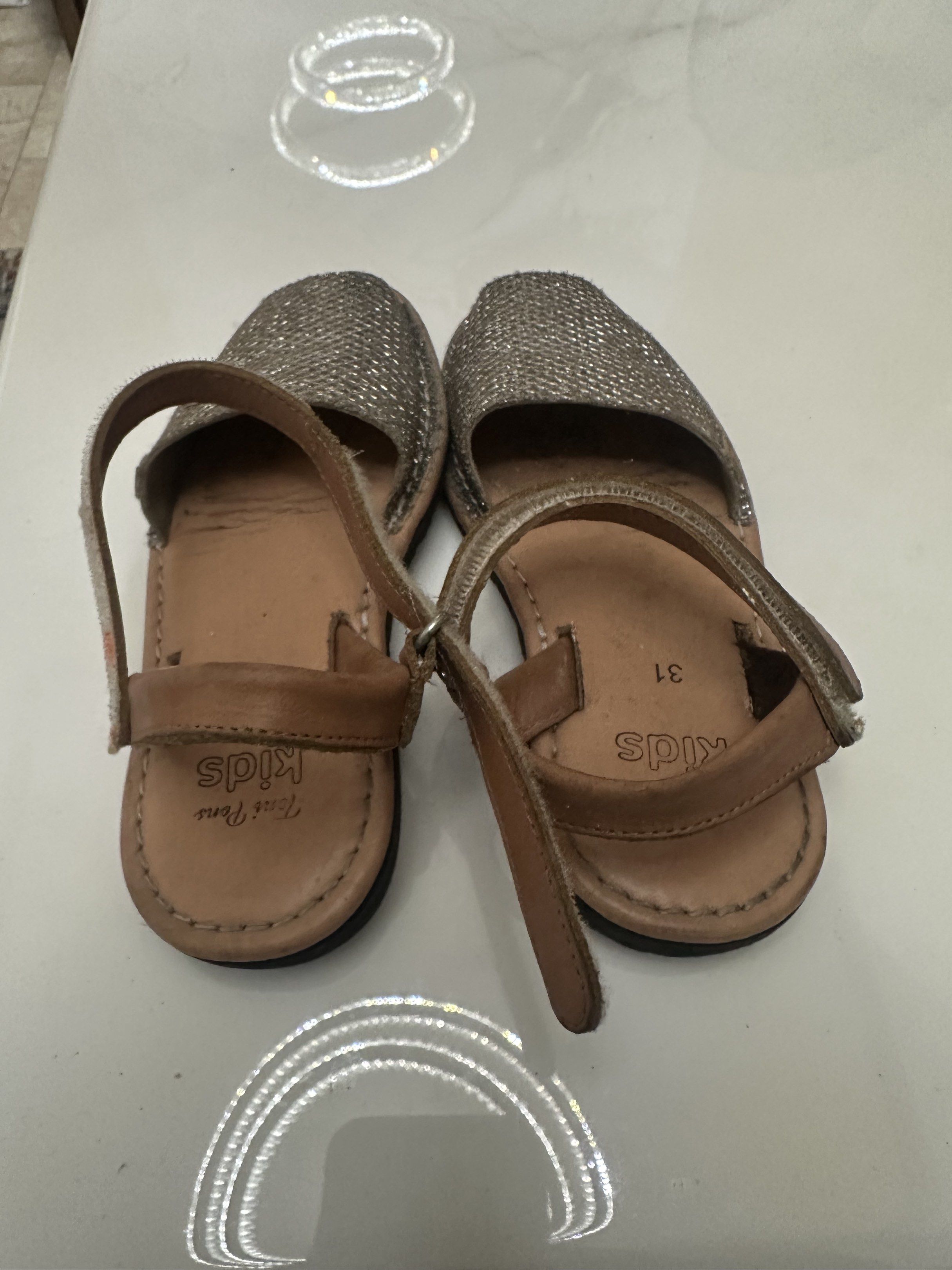 Toni Pons kids shoes (Category: Babies & Kids Fashion) located in Antipolo. Submitted by capizexport (Listing ID 1419523745, Image 3). Description: - Toni Pons - Size 31 - Silver glitter upper - Brown leather strap - Black soles with textured pattern - Hook-and-loop closure - Well-maintained condition Price 500 pesos .