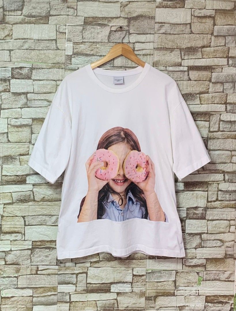 Acme De La Vie Donut Graphic Tee (Category: Tshirts & Polo Shirts ) located in Caloocan City. Submitted by vintstreets (Listing ID 1419734332, Image 1). Description: ADLV • Dimes: width: 22 Length: 28 • Condition & Color rate: 9.2/10 • makapal tela • solid print nito • light stain pinaka ilalim pero hindi sya visible ha 📍 South Caloocan 🚚 JNT - ADLV white t-shirt - Features a graphic of a girl holding donuts - Brand name printed on the back - S
