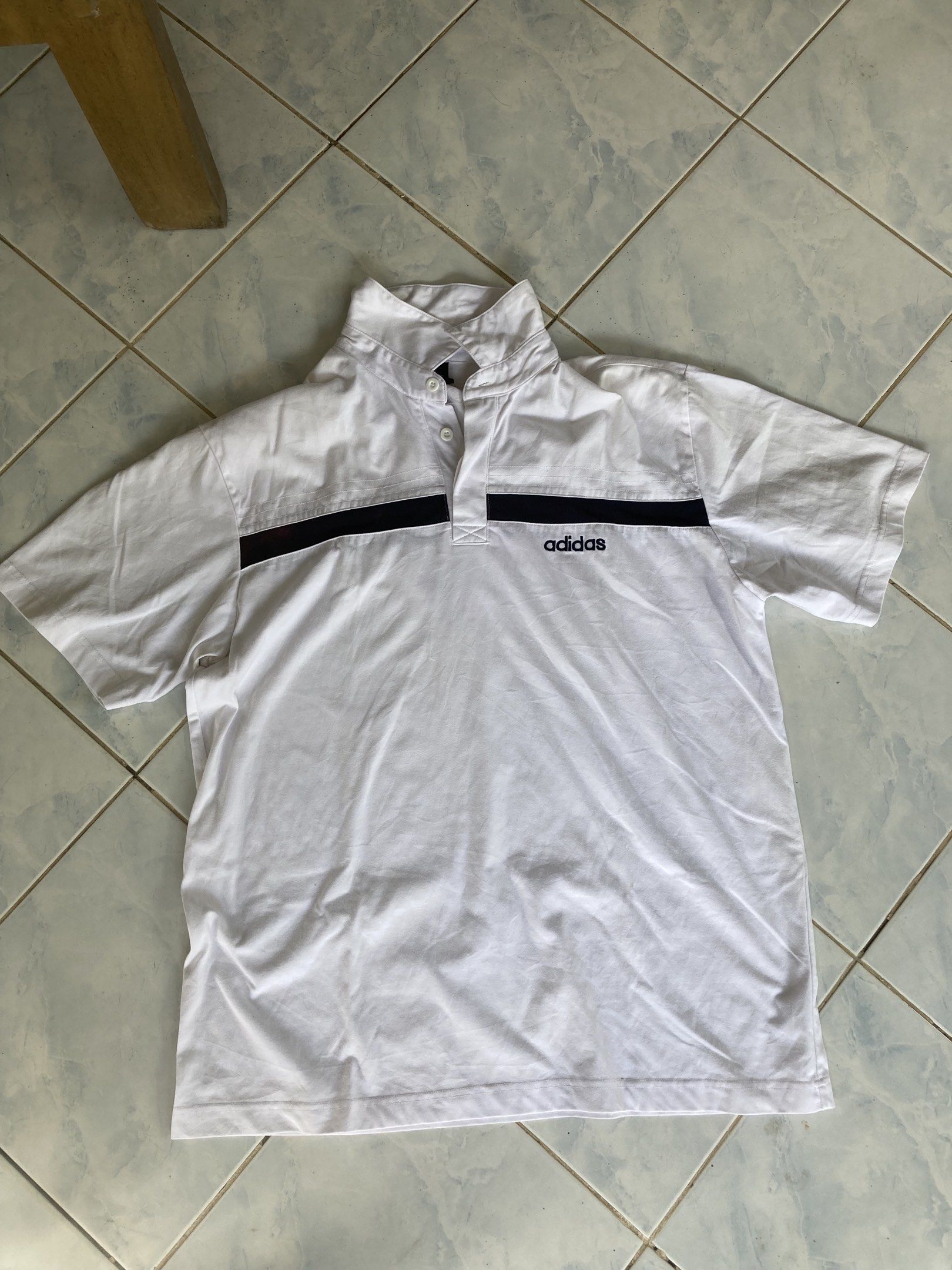 Adidas White Polo Shirt (Category: Tshirts & Polo Shirts ) located in Tarlac. Submitted by everthrift (Listing ID 1419776860, Image 1). Description: - White Adidas polo shirt - Black stripes across chest and back - High collar - Adidas logo on chest - Short sleeves - Button-up neckline - Minor discoloration on back stripe.