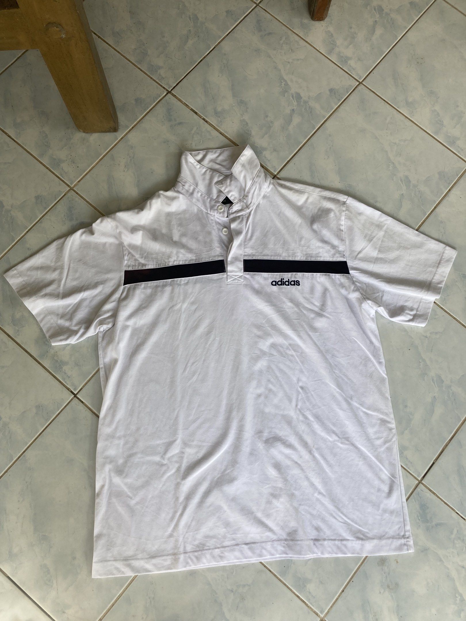Adidas White Polo Shirt (Category: Tshirts & Polo Shirts ) located in Tarlac. Submitted by everthrift (Listing ID 1419776860, Image 3). Description: - White Adidas polo shirt - Black stripes across chest and back - High collar - Adidas logo on chest - Short sleeves - Button-up neckline - Minor discoloration on back stripe.