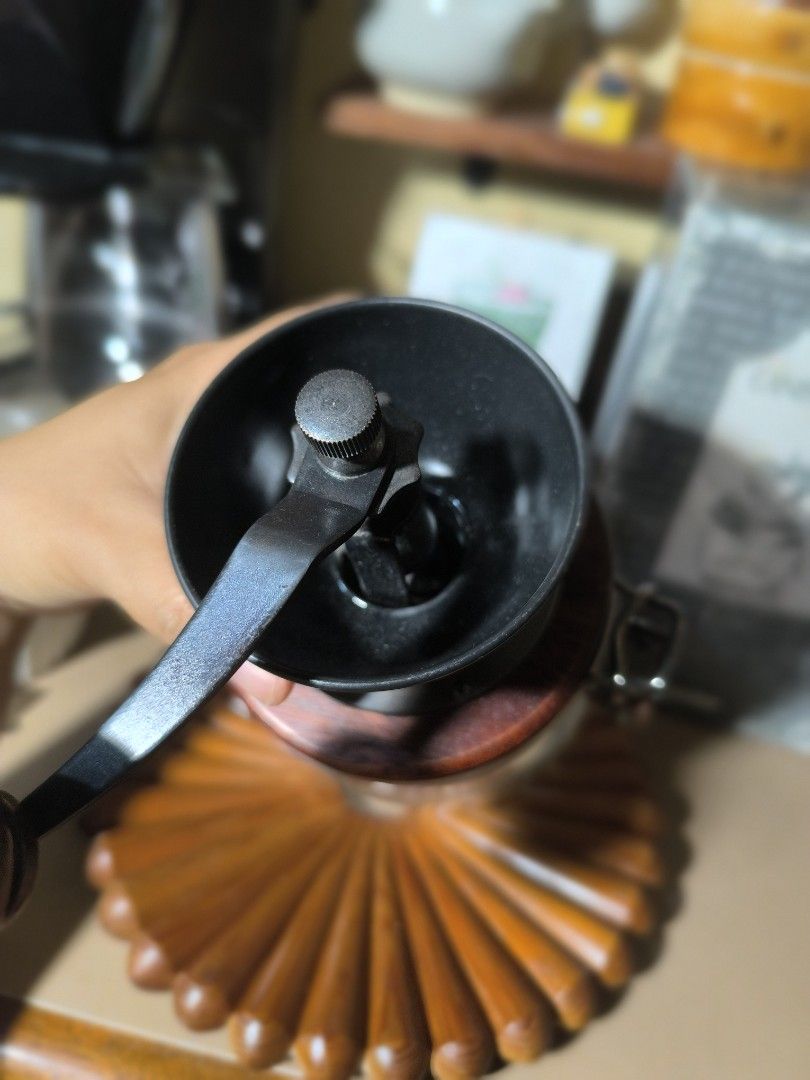 Hario Canister Mill Coffee Grinder (Category: Coffee & Tea Tableware) located in Pangil. Submitted by kopee_matcha (Listing ID 1419730464, Image 3). Description: - Hario Canister Mill coffee grinder - Features a glass jar - Wooden lid included - Metal grinding mechanism - Manual hand crank for grinding - Airtight design - Comes with the original box.