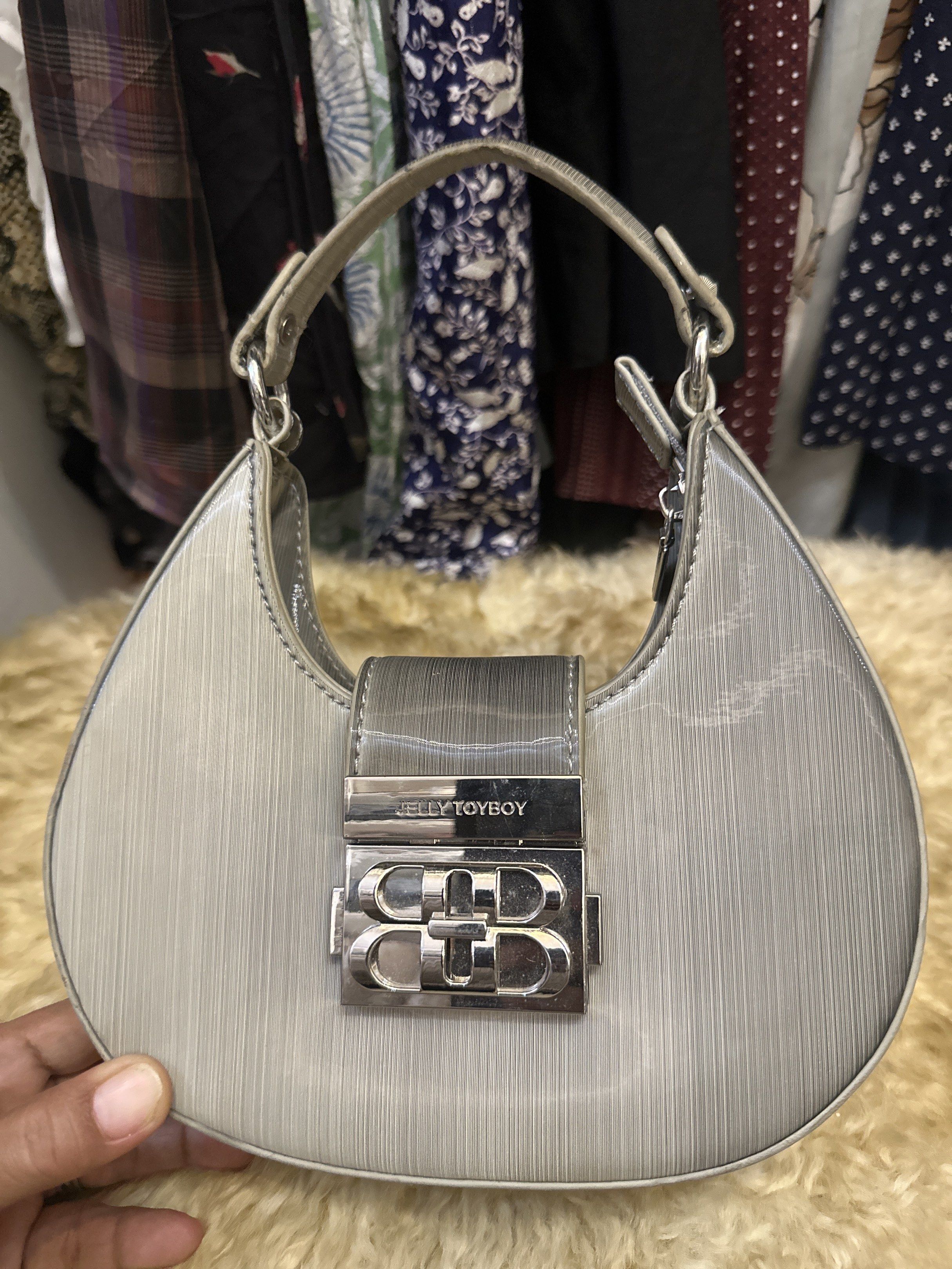 Kelly Toyboy Silver Handbag (Category: Luxury Bags & Wallets) located in Digos. Submitted by puremountain.6f1756 (Listing ID 1419640289, Image 1). Description: - Silver handbag - Brand: Kelly Toyboy - Unique shape - Top handle - Silver clasp closure - Textured surface - Interior pocket - Dimensions: Approximately 20cm (H) x 22cm (W) Note: bawal sa maarte , I am selling my collection to support my daughter. I am single mom. .