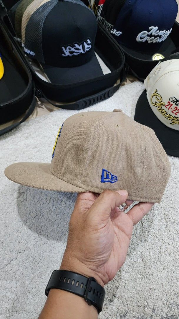 New Era Golden State Warriors Cap (Category: Caps & Hats) located in Quezon City. Submitted by rg_store (Listing ID 1419656592, Image 3). Description: - Golden State Warriors cap - Tan color with blue and yellow accents - Features the Warriors logo on the front - Flat brim design - Adjustable blue strap at the back - Includes NBA and New Era logos - "Western Conference" patch on the side No stickers.