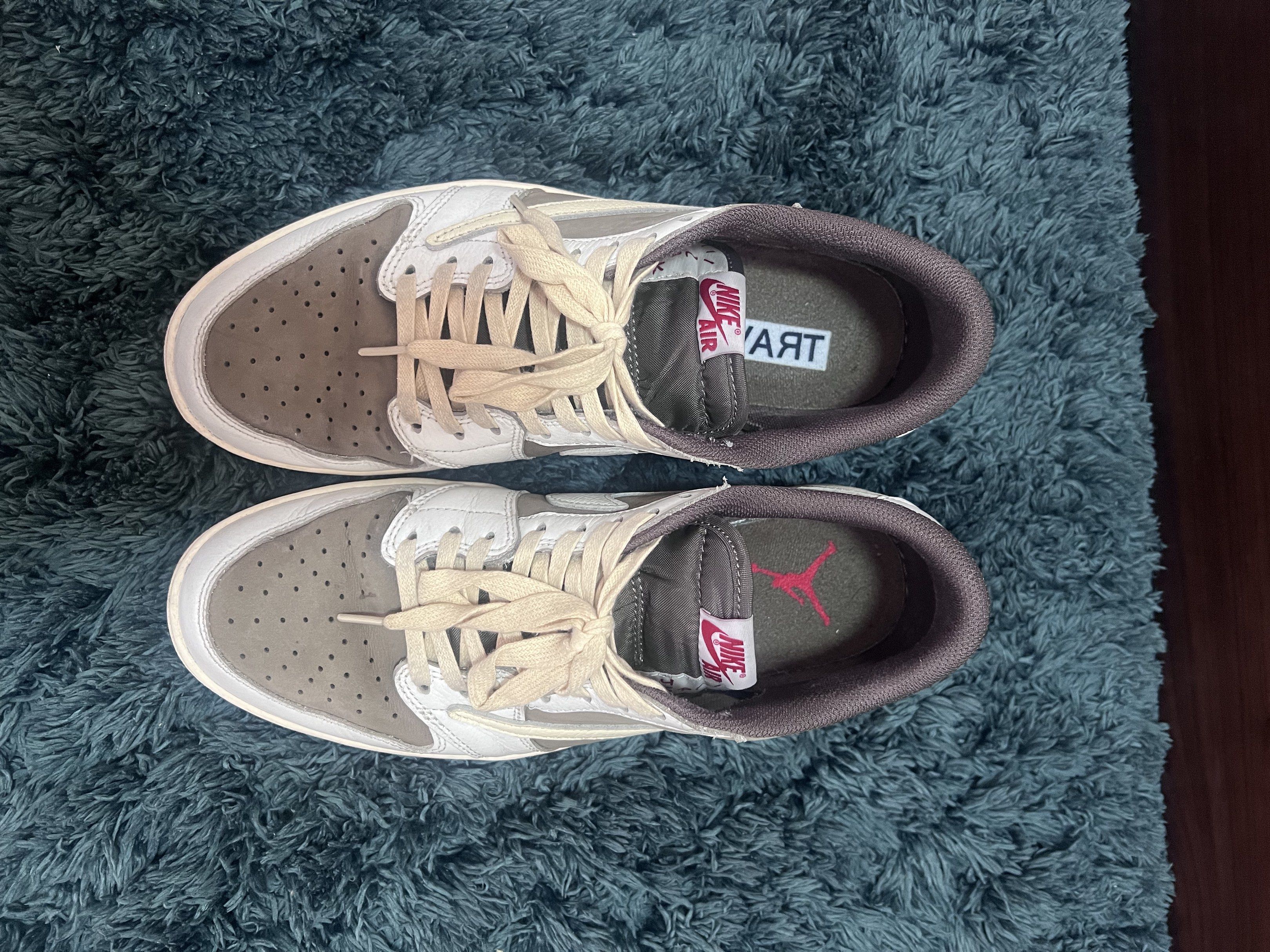 Nike Air Jordan 1 Low Travis Scott (Category: Sneakers) located in Manila. Submitted by julia.irene (Listing ID 1419651569, Image 3). Description: These sneakers feature a white and brown colorway with the iconic Travis Scott design elements. The shoes have the Air Jordan logo on the back and the Travis Scott face logo on the other. The soles are brown. The insoles have the Nike Air logo and the word "TRAV" on one shoe and the Air Jordan logo on 