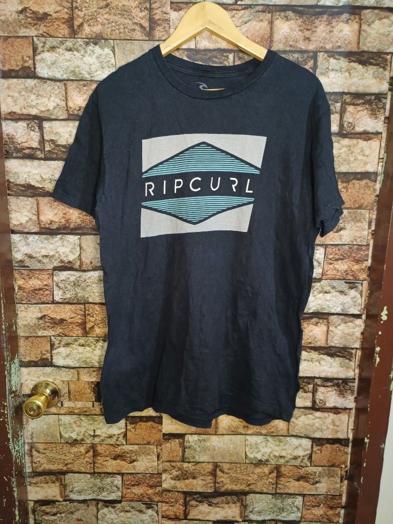 RIP CURL BOARD SHIRT (Category: Tshirts & Polo Shirts ) located in Manila. Submitted by -cheekonah_finds (Listing ID 1419708114, Image 1). Description: - Dark blue Rip Curl t-shirt - Graphic print on the front - Crew neck - Short sleeves - Soft material - Features Rip Curl brand name in a rectangular shape with a geometric pattern.