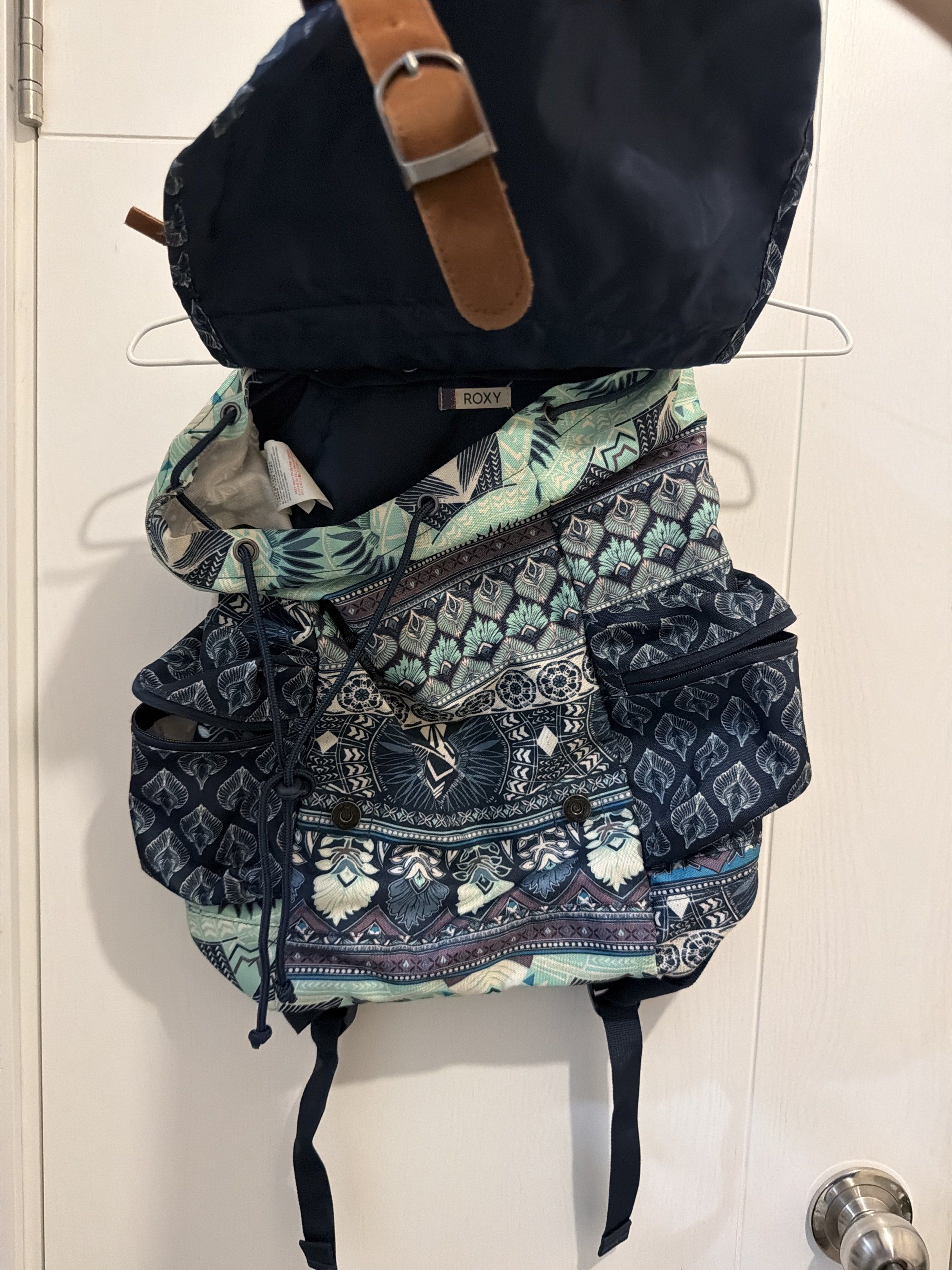 Roxy Patterned Backpack （分類：背囊）位於 Hong Kong。 由 chambertininhk 提交（商品編號 1419715722，圖片 2）。簡介： Roxy backpack features a unique patterned design with brown leather-like straps and buckles. It has multiple compartments, including side pockets and a drawstring closure. The backpack also has a top handle and adjustable shoulder straps. The interior lining is a solid navy blue. The backpack is suitable for carrying books, personal items, or travel essenti