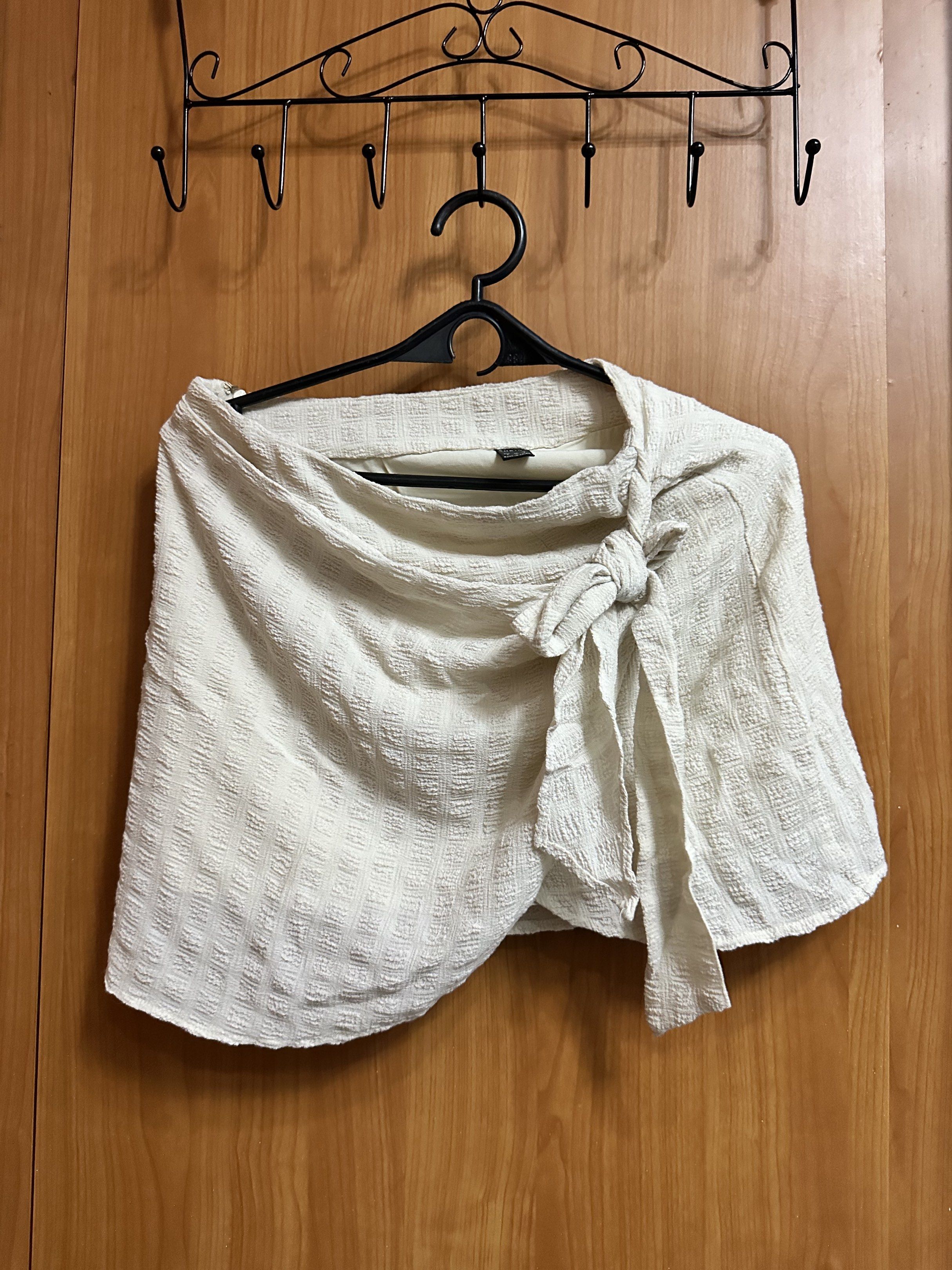 SHEIN Wrap Skirt (Category: Skirts) located in Manila. Submitted by ryryrys (Listing ID 1419629588, Image 1). Description: - SHEIN cream-colored wrap skirt - Size: S - Features textured fabric - Tie closure - Versatile for casual wear.