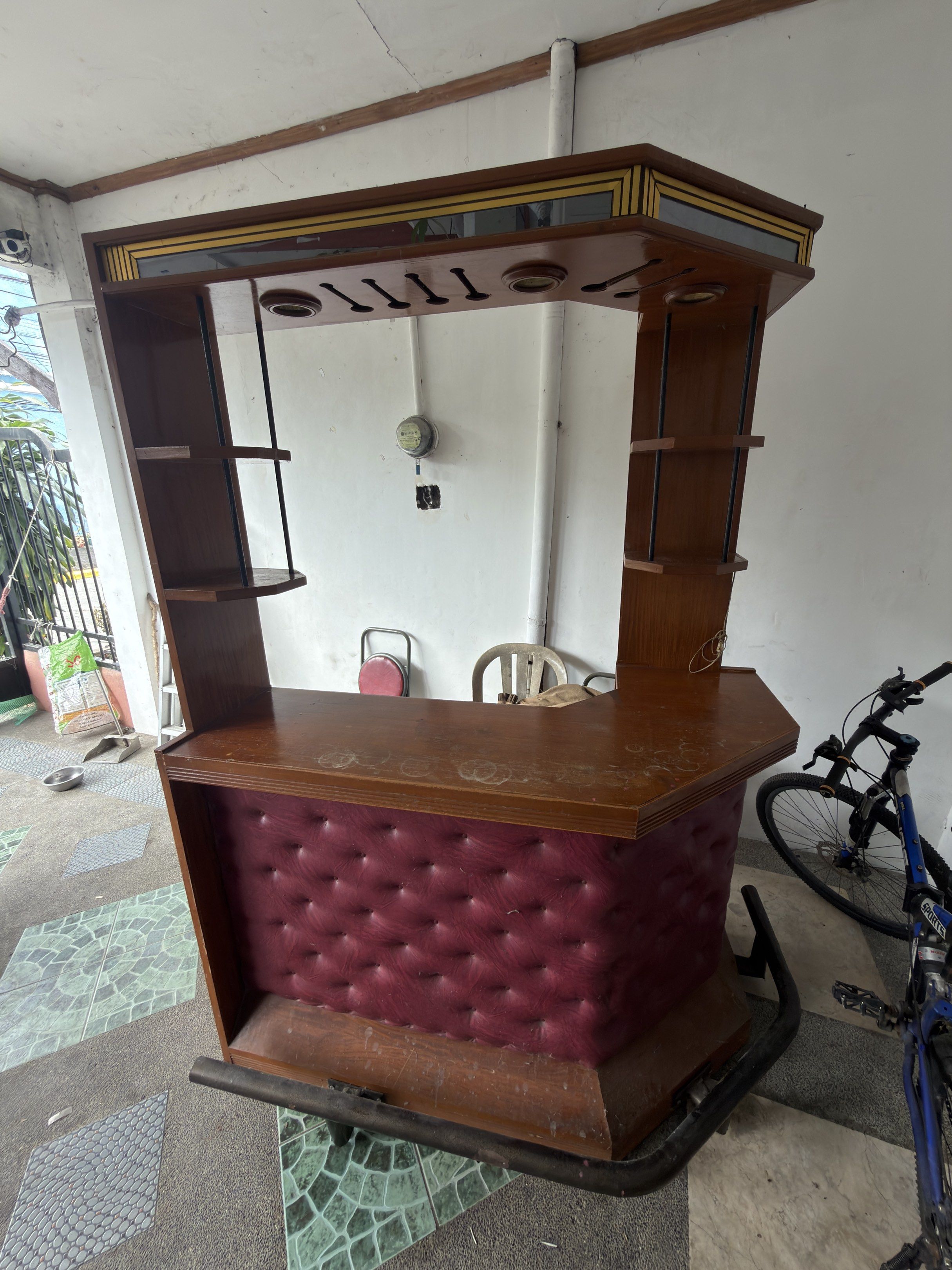 Wooden Bar with Shelves (Category: Shelves, Cabinets & Racks) located in Manila. Submitted by khaazzii11 (Listing ID 1419730047, Image 3). Description: - Wooden bar with multiple shelves - Built-in wine glass rack - Countertop included - Burgundy upholstered front - Built-in lighting - Unique corner design with side shelving - Perfect for home entertainment or small business use.