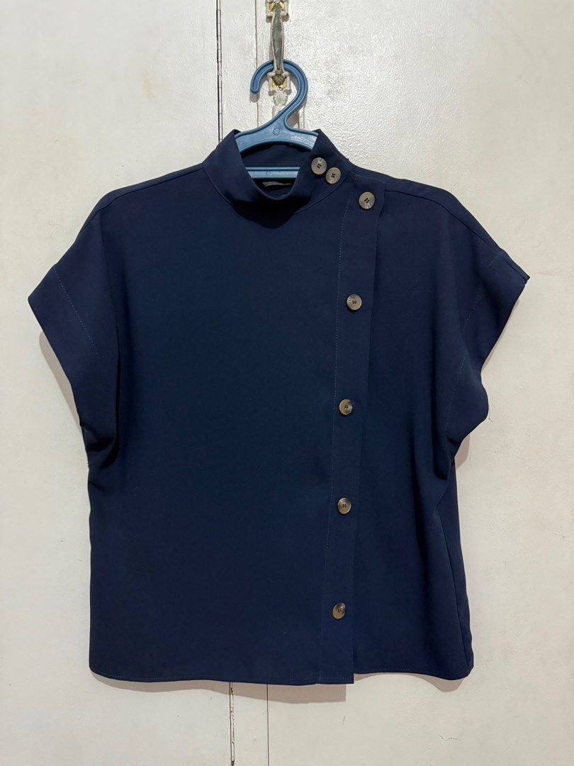 Zara Navy Blue High Neck Blouse (Category: Sleeveless) located in Malabon City. Submitted by decluttergyal (Listing ID 1419716475, Image 1). Description: - Zara navy blue top - Color: Navy blue - Size XS but can fit an S or even an M. - Features: Mock neck, button details on front, short sleeves - Made in Morocco - Used once for a work event then never again Tags: zara, blouse, work attire, mango, massimo dutti.