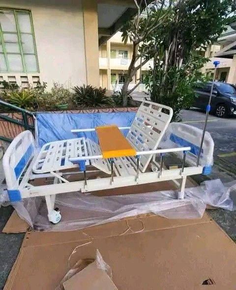 Adjustable Hospital Bed with Accessories (Category: Medical Supplies & Tools) located in Quezon City. Submitted by gentlewater_b4735d (Listing ID 1419789283, Image 3). Description: - Adjustable hospital bed - Includes wooden over-bed table - Comes with IV drip stand - White frame with blue accents - Blue mattress cover - Adjustable head and foot sections - Suitable for home and clinical use.