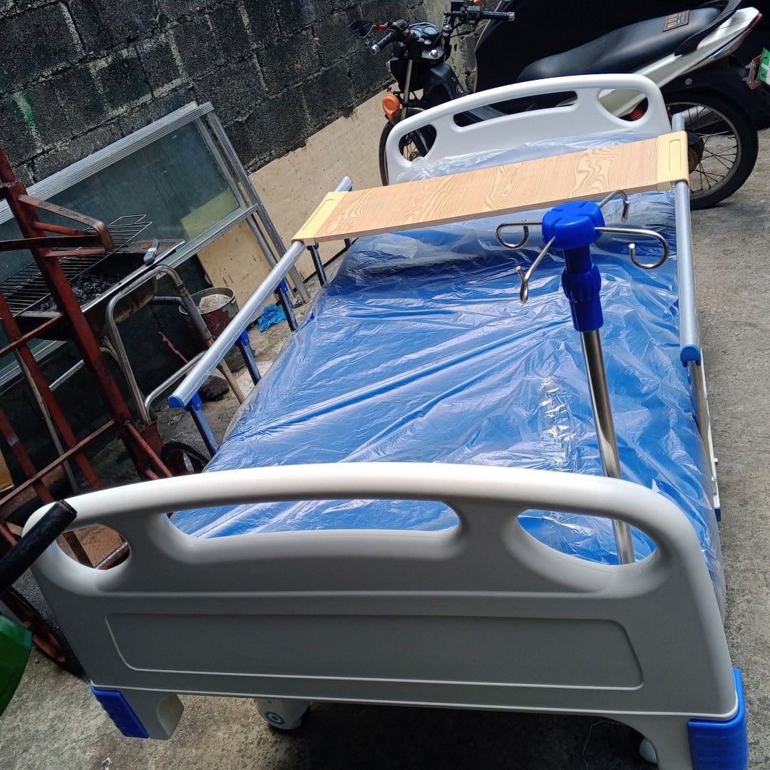 Adjustable Hospital Bed with Accessories (Category: Medical Supplies & Tools) located in Quezon City. Submitted by gentlewater_b4735d (Listing ID 1419789283, Image 2). Description: - Adjustable hospital bed - Includes wooden over-bed table - Comes with IV drip stand - White frame with blue accents - Blue mattress cover - Adjustable head and foot sections - Suitable for home and clinical use.