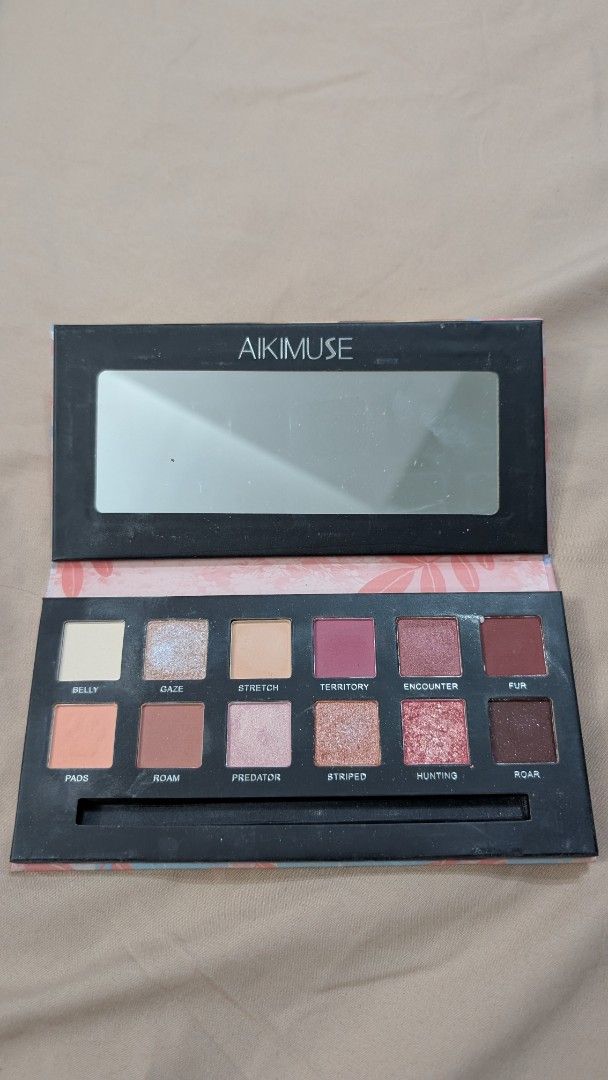 Aikimuse Eyeshadow Palette (Category: Makeup) located in San Fernando. Submitted by jctut (Listing ID 1419806869, Image 2). Description: - Aikimuse eyeshadow palette - Includes a mirror - Features a range of pink, brown, and neutral eyeshadow shades - Suitable for creating different makeup looks - Floral design inside the palette.